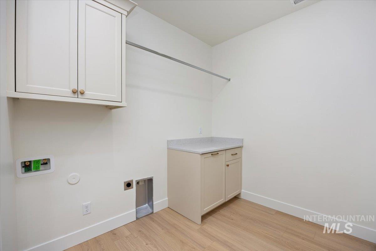 Laundry room with light wood-style floors, cabinet space, and hookup for an electric dryer