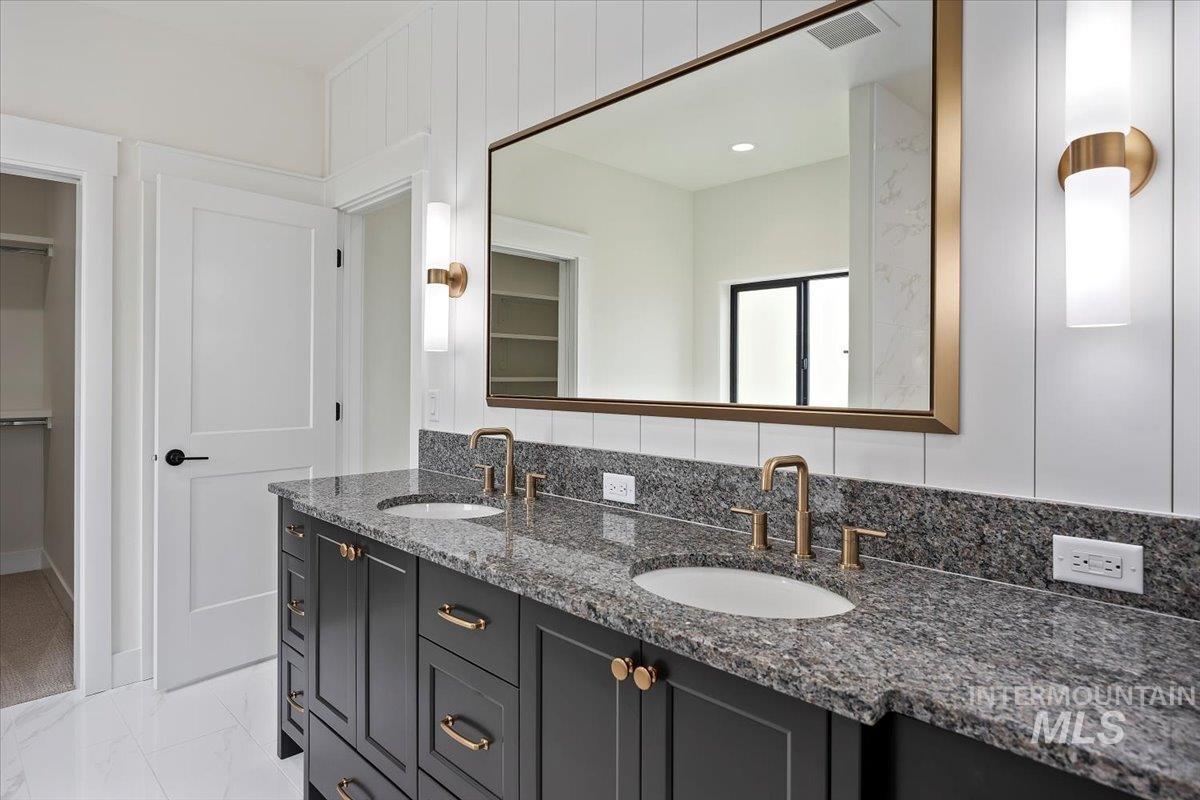 Bathroom with double vanity and a walk in closet