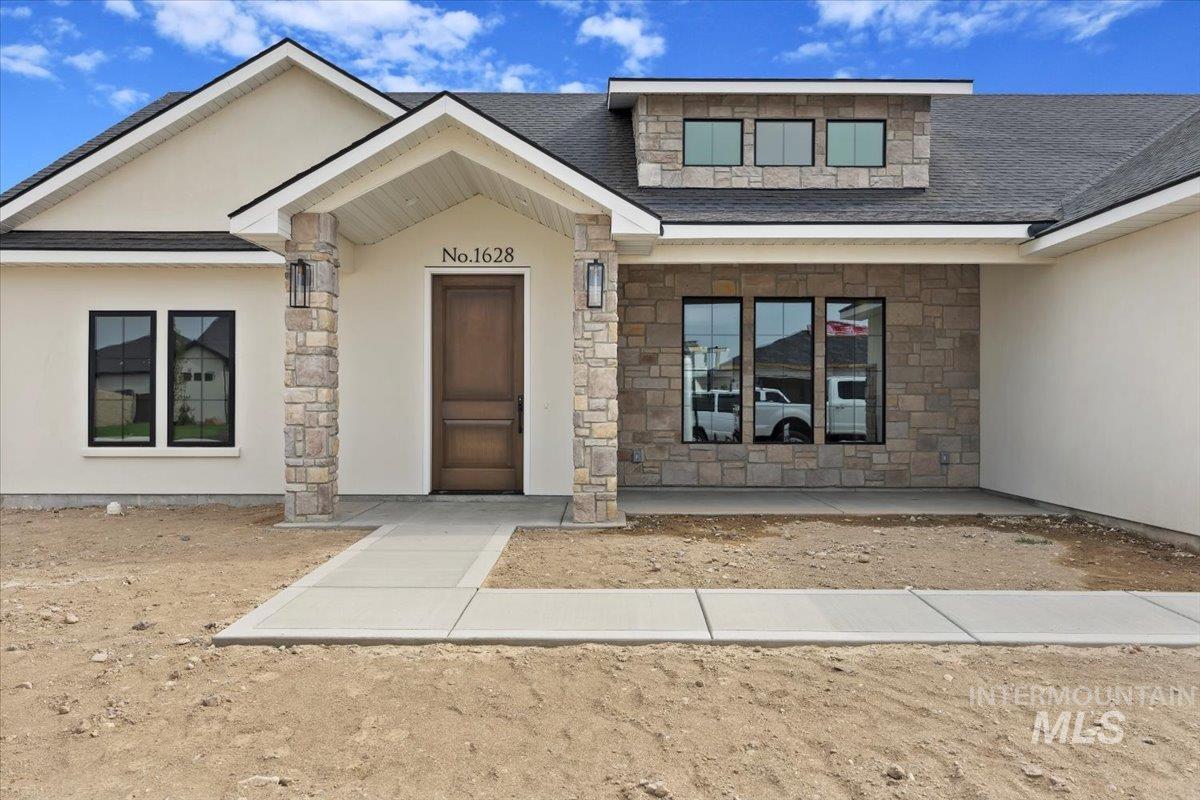 View of exterior entry featuring stone siding, stucco siding, and roof with shingles