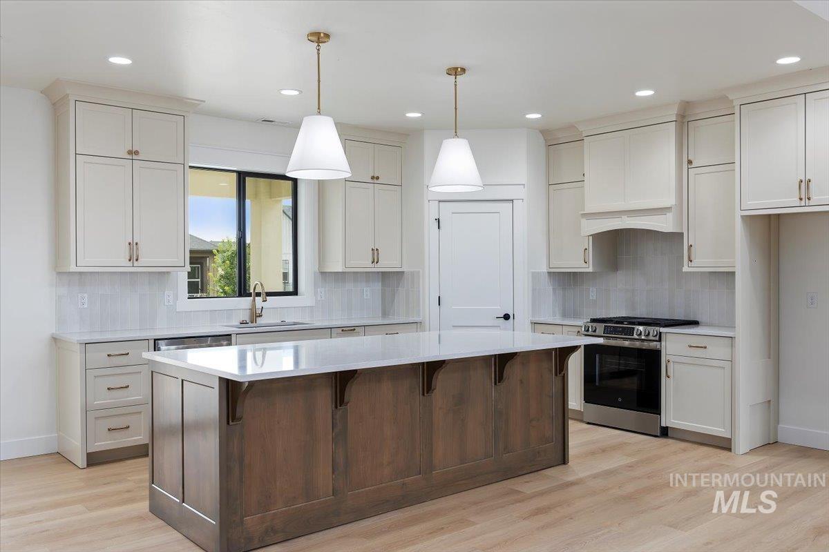 Kitchen with stainless steel gas stove, a breakfast bar, recessed lighting, backsplash, and dark brown cabinetry