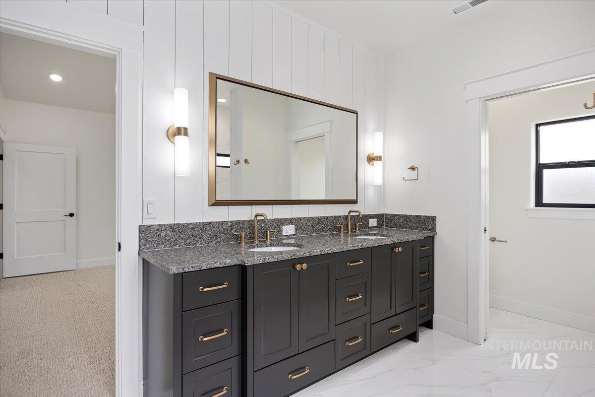 Full bathroom with double vanity, light marble finish floors, and recessed lighting