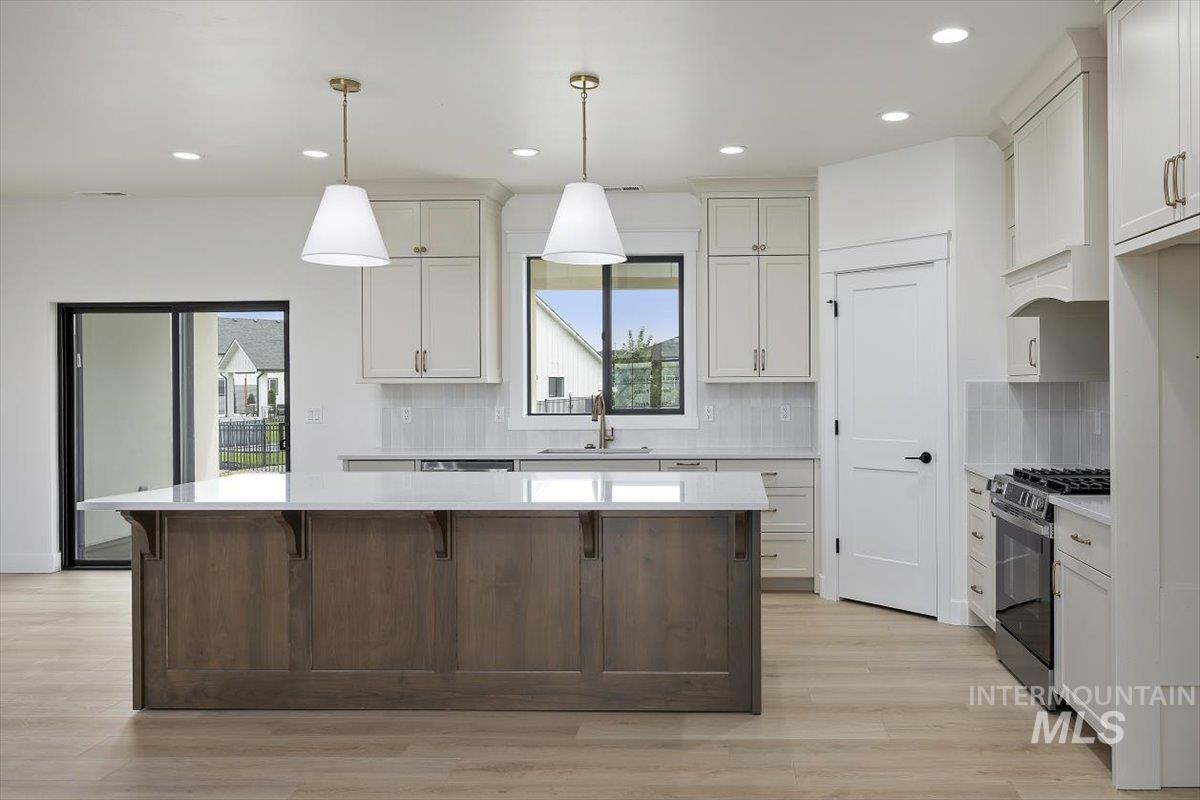 Kitchen with backsplash, stainless steel gas range oven, recessed lighting, a kitchen island, and decorative light fixtures