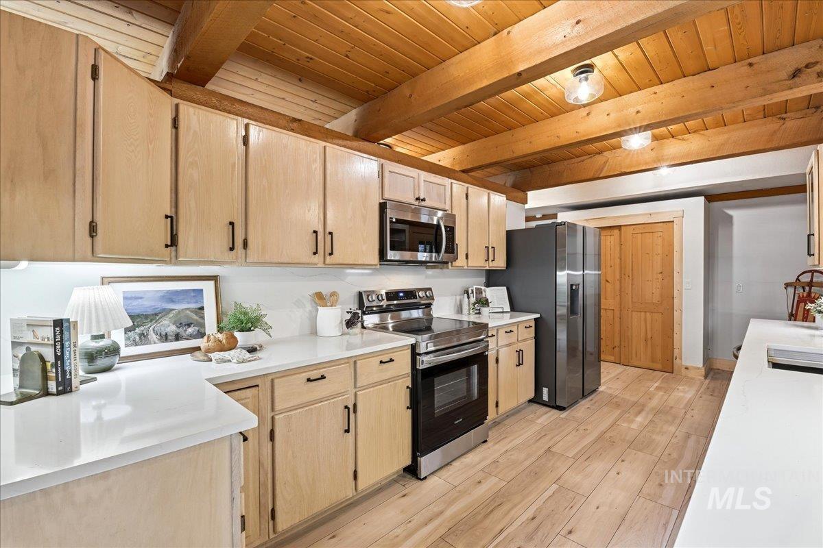 Kitchen with wood-finish flooring and a wood plank ceiling featuring exposed beams