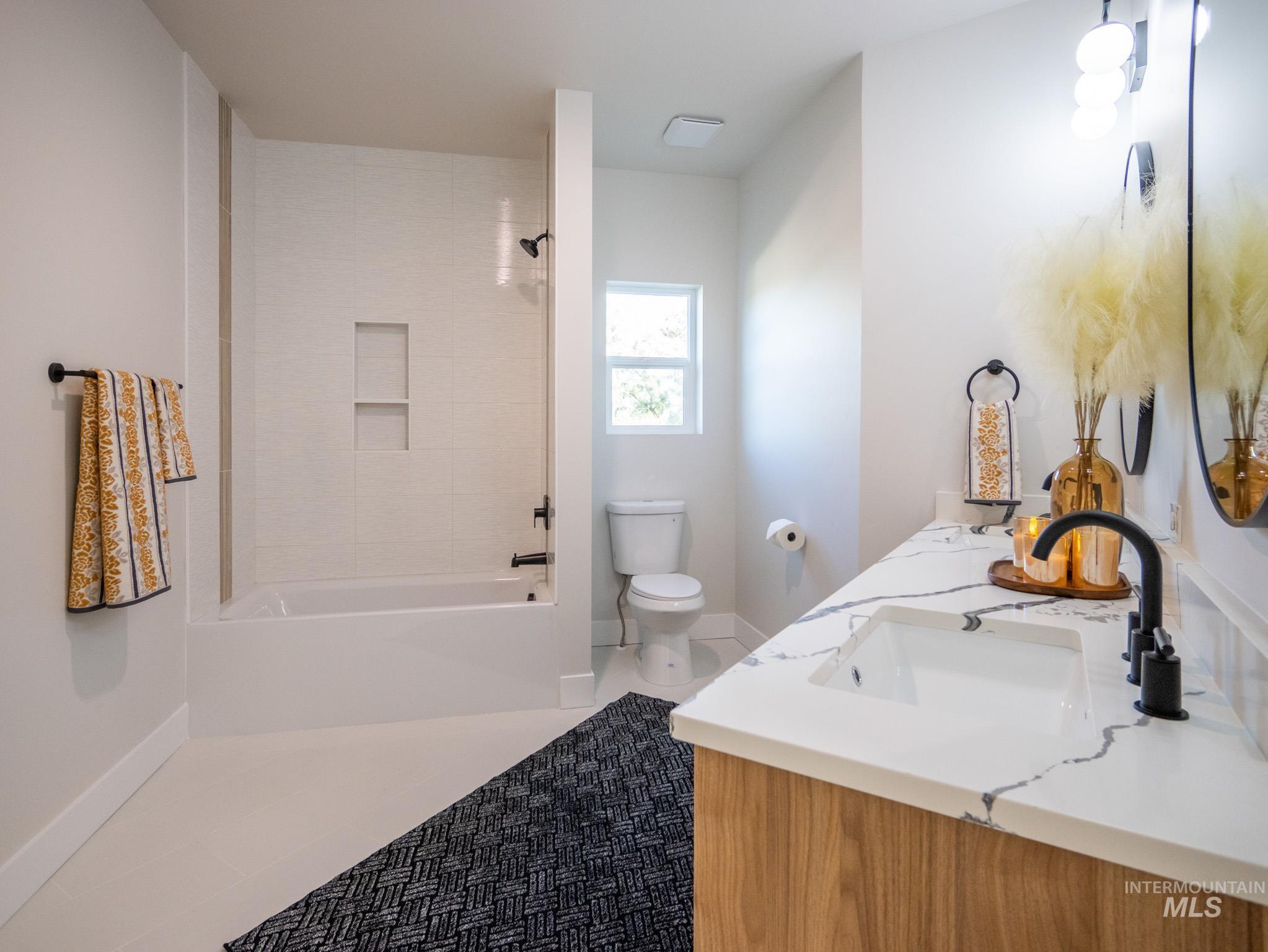 Full bath with double vanity, tile patterned floors, and tub / shower combination