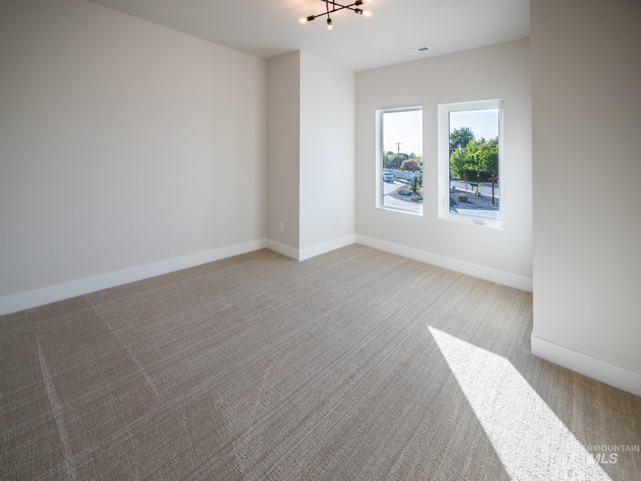 Unfurnished room featuring light colored carpet and a chandelier