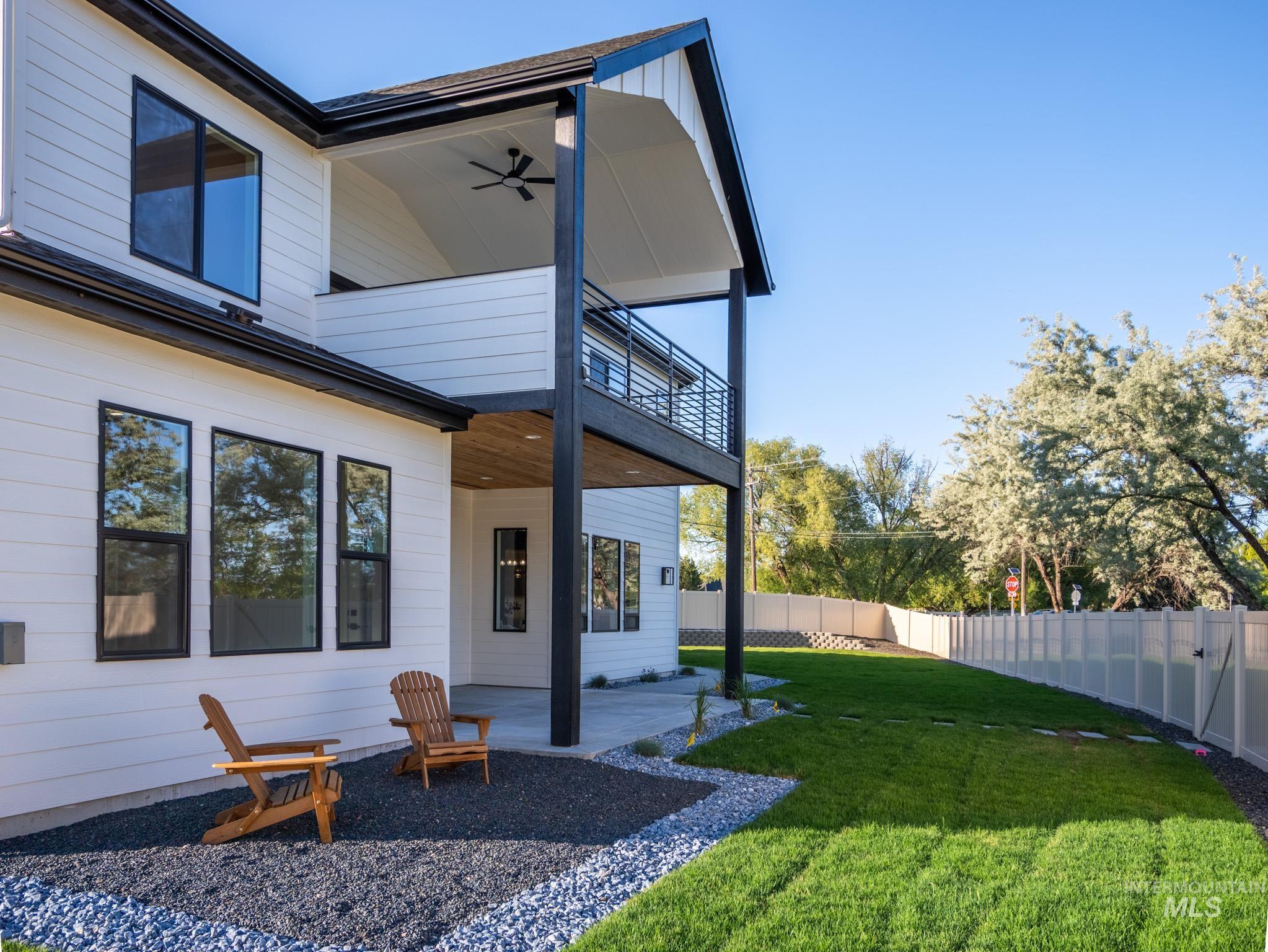Fenced backyard with a patio area, a ceiling fan, and a balcony