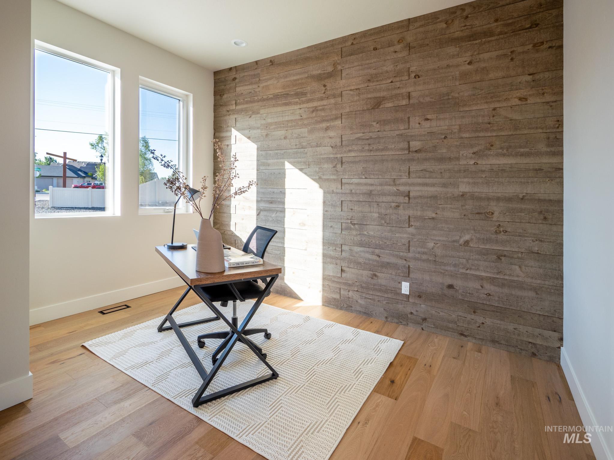 Office space featuring wooden walls, light wood finished floors, and an accent wall