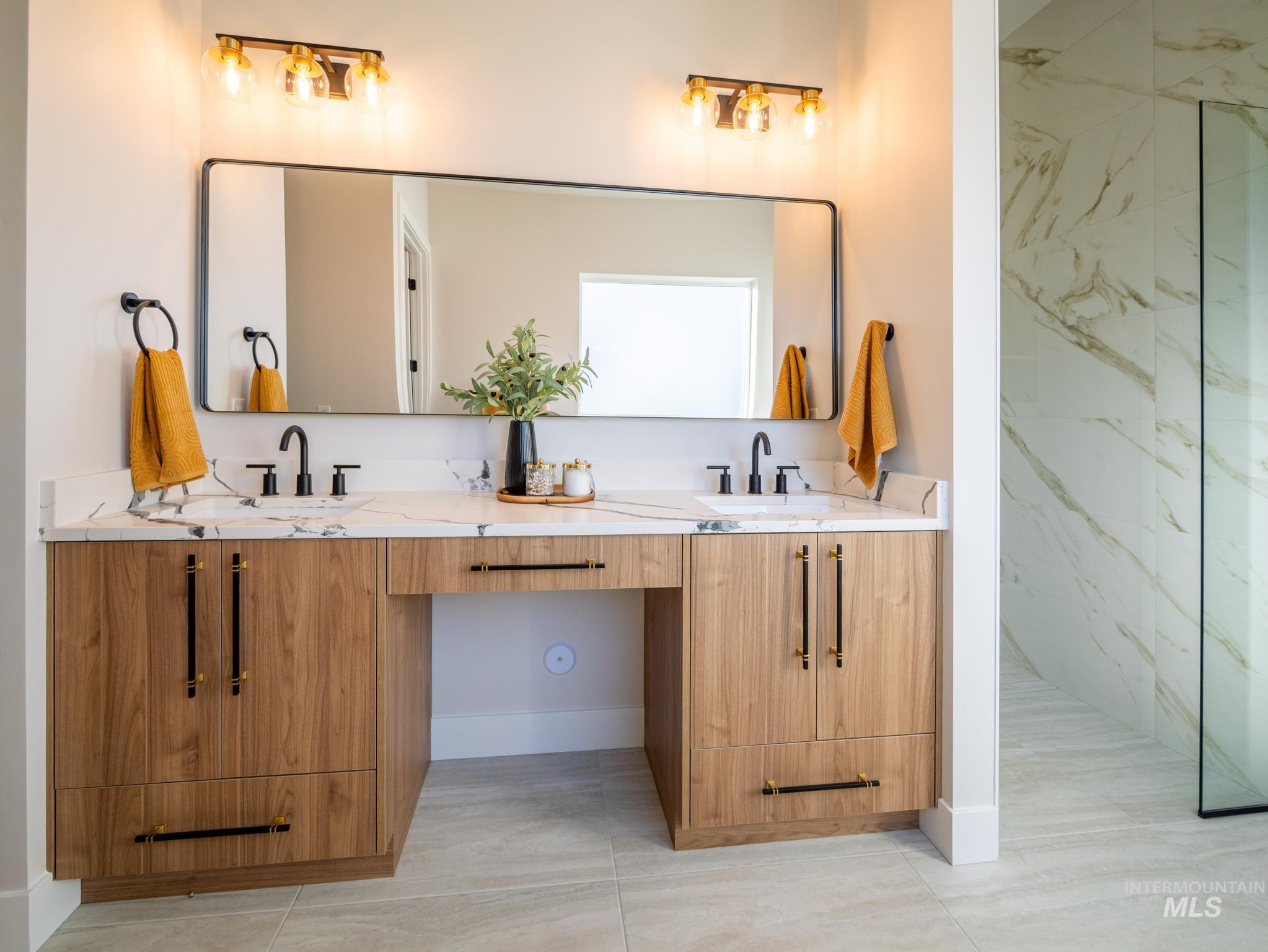 Bathroom featuring double vanity, light tile patterned flooring, and a marble finish shower