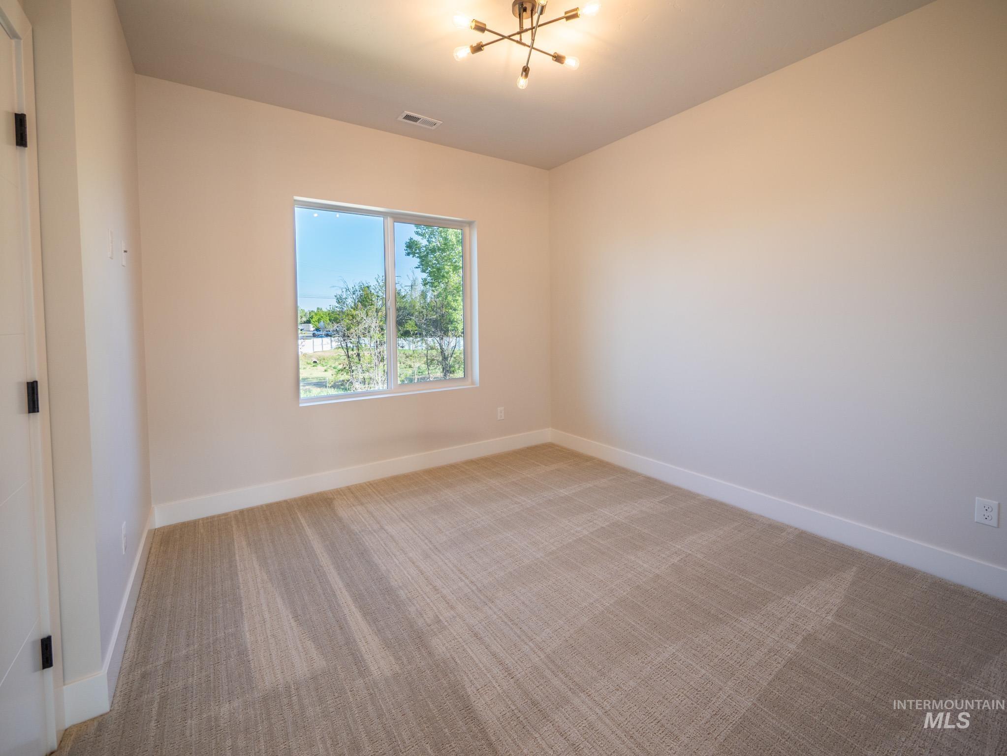 Spare room featuring light carpet and a chandelier