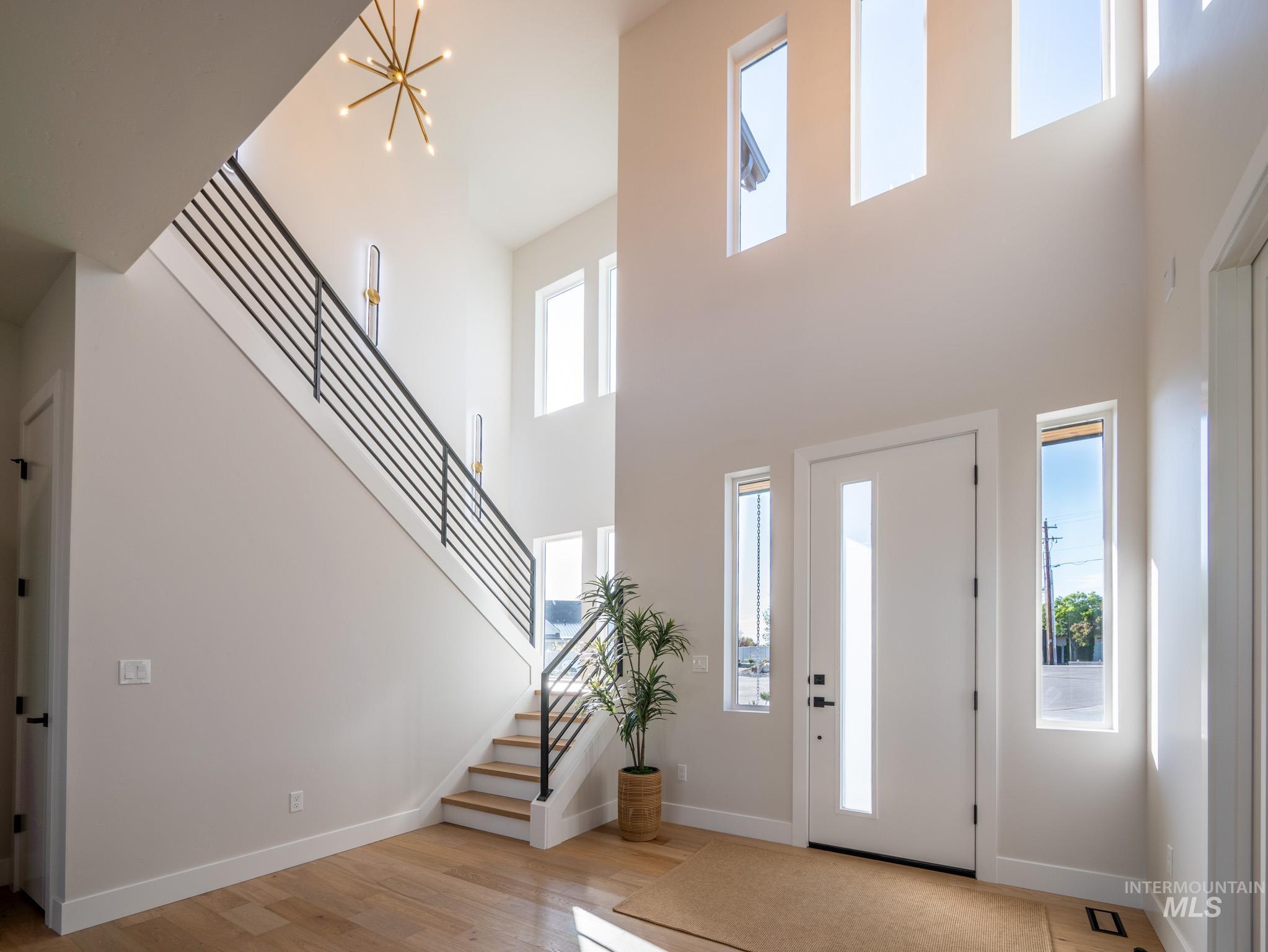 Entryway with plenty of natural light, stairs, a high ceiling, and light wood-style floors