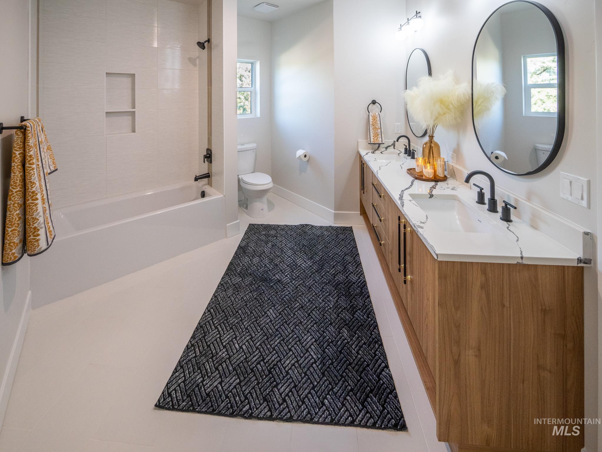 Full bathroom with double vanity, shower / bathtub combination, and light tile patterned flooring