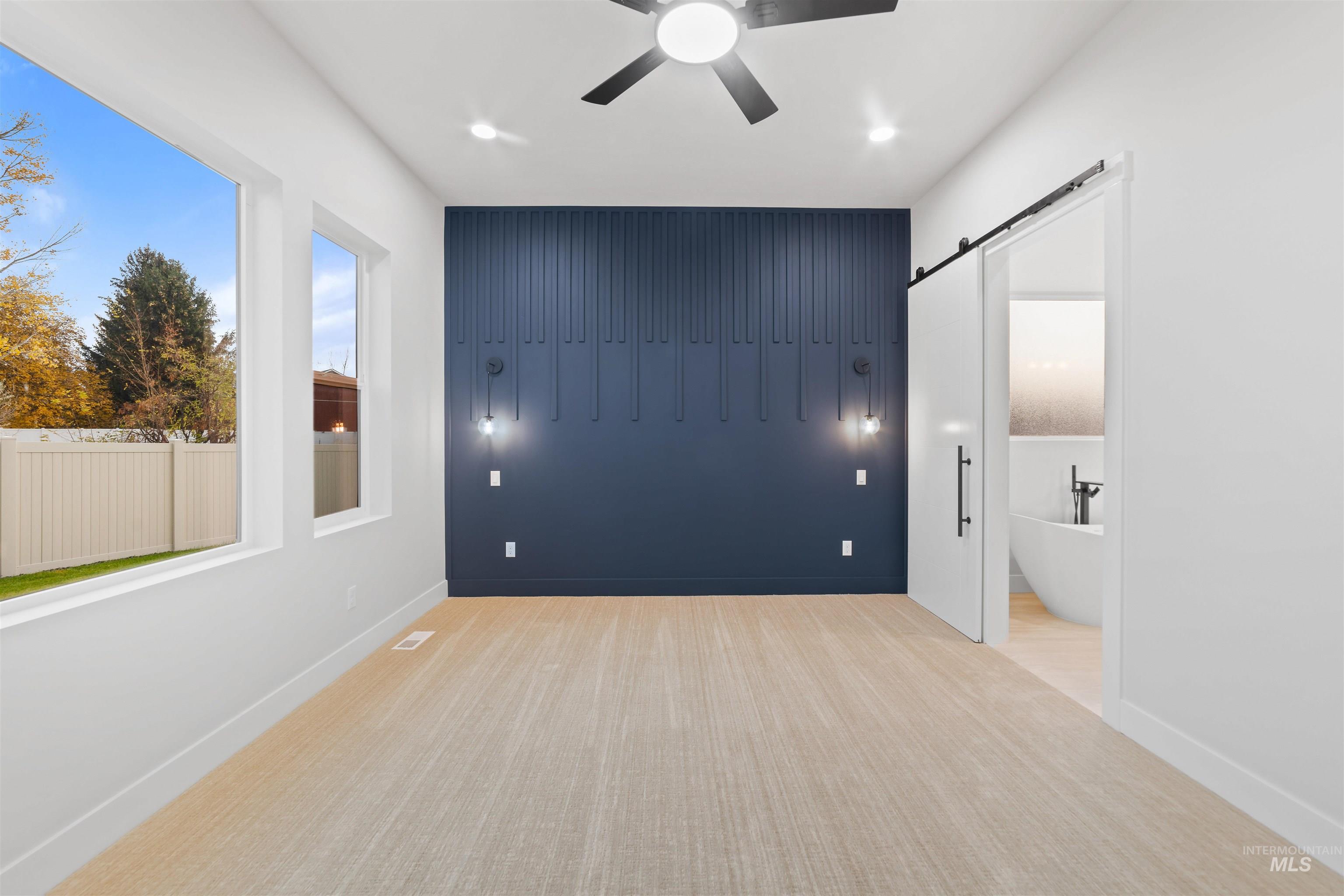 Empty room with a barn door, light colored carpet, a ceiling fan, and recessed lighting