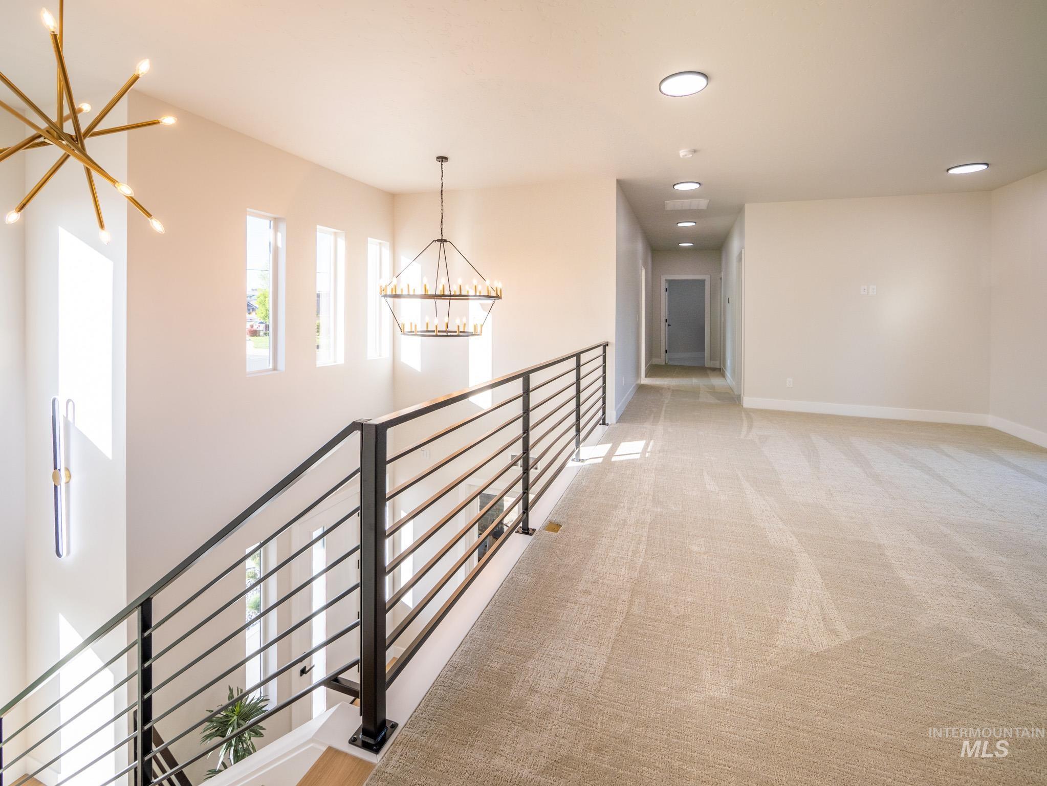 Hallway with a chandelier, recessed lighting, light colored carpet, and an upstairs landing