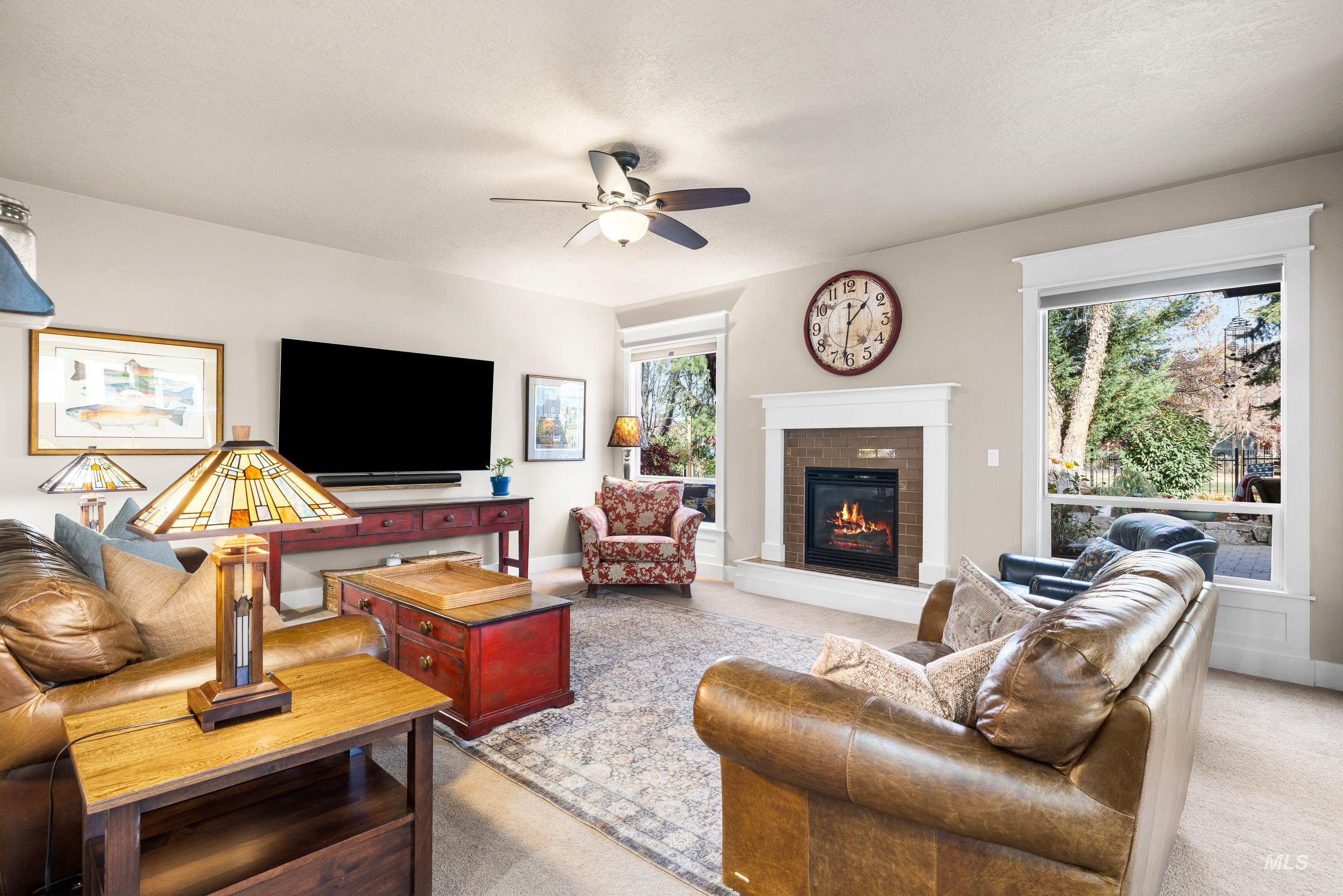 Living area featuring plenty of natural light, light carpet, a fireplace, and ceiling fan