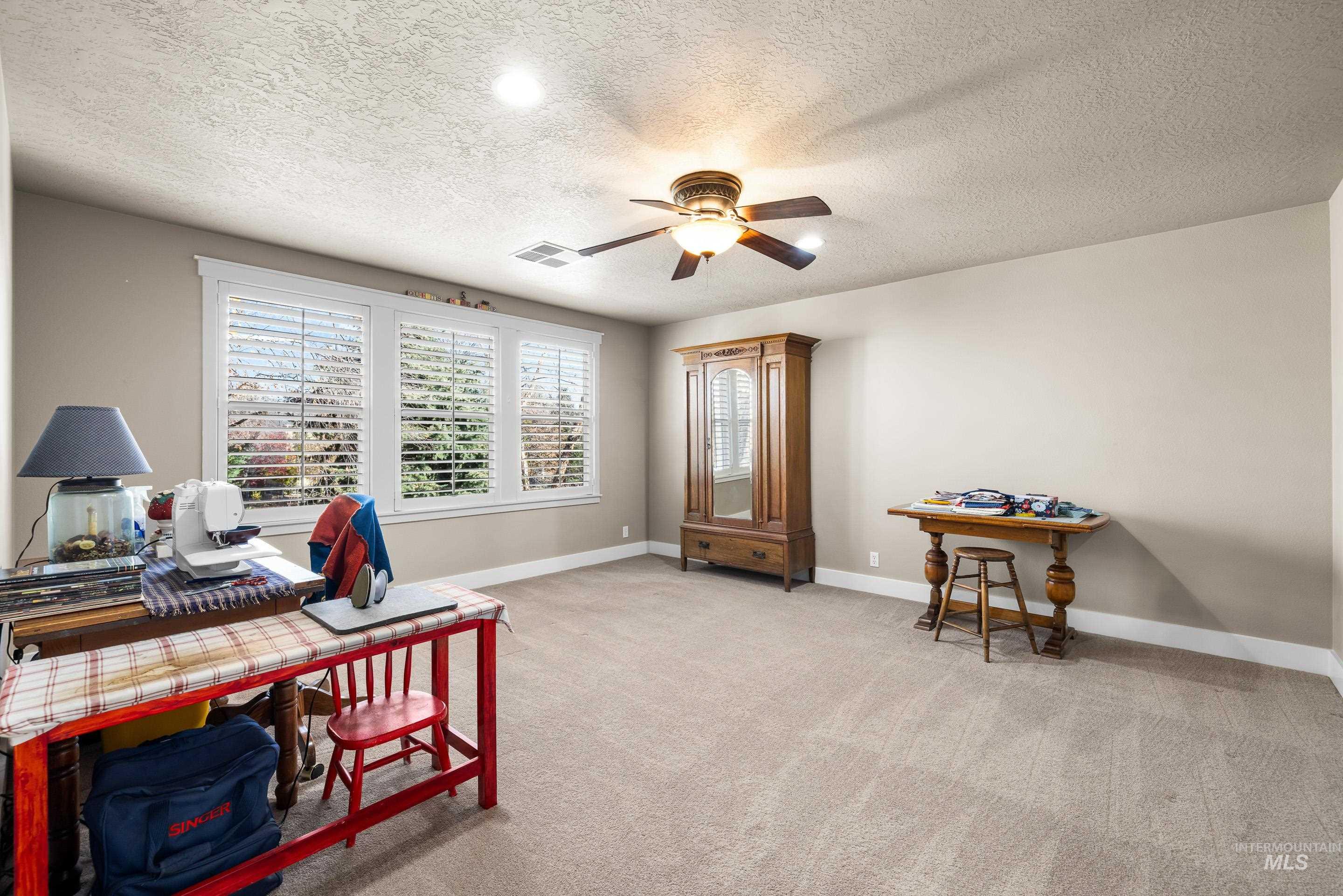 Office area with light carpet, a textured ceiling, and ceiling fan