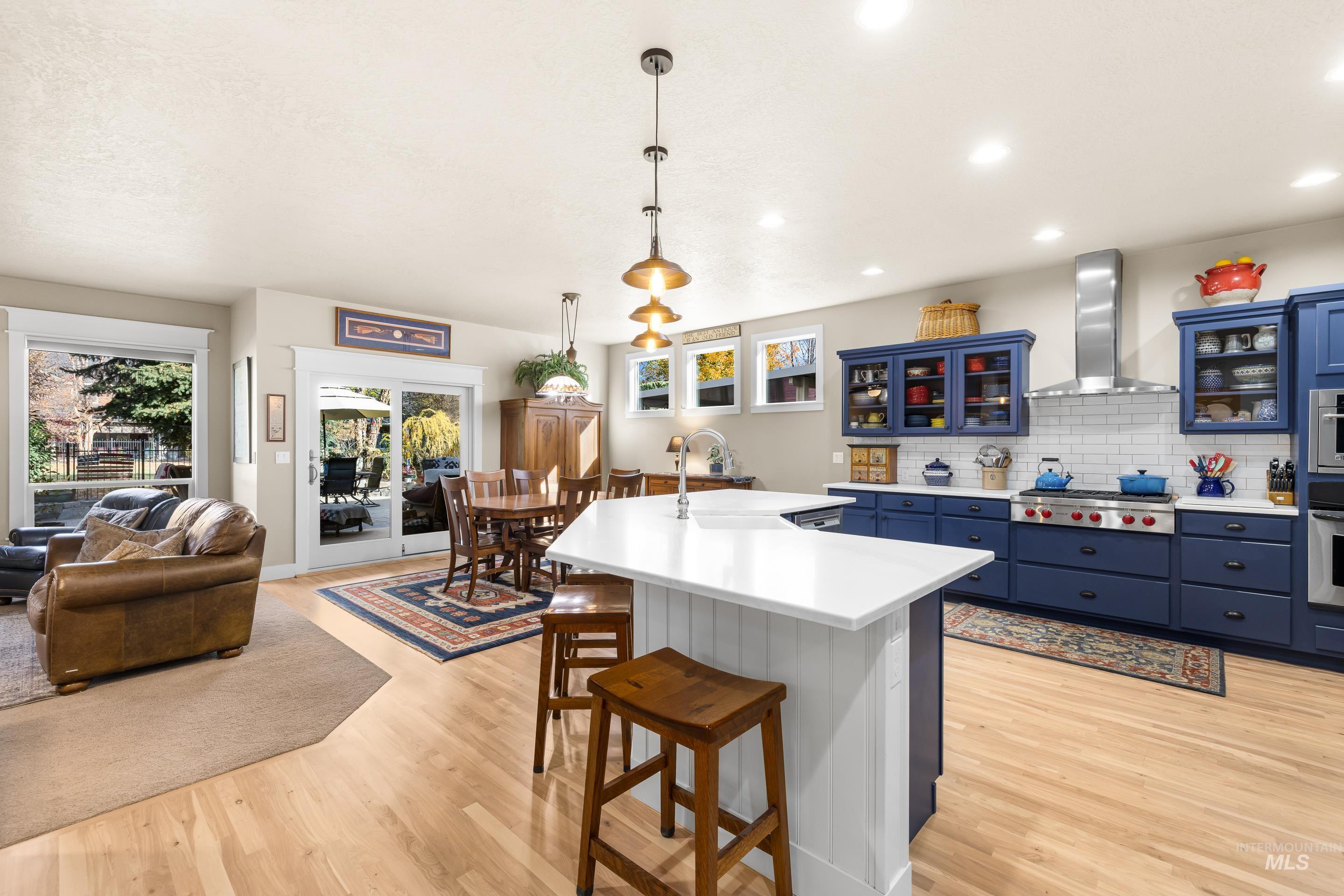 Kitchen featuring blue cabinetry, glass insert cabinets, tasteful backsplash, light countertops, and a kitchen breakfast bar
