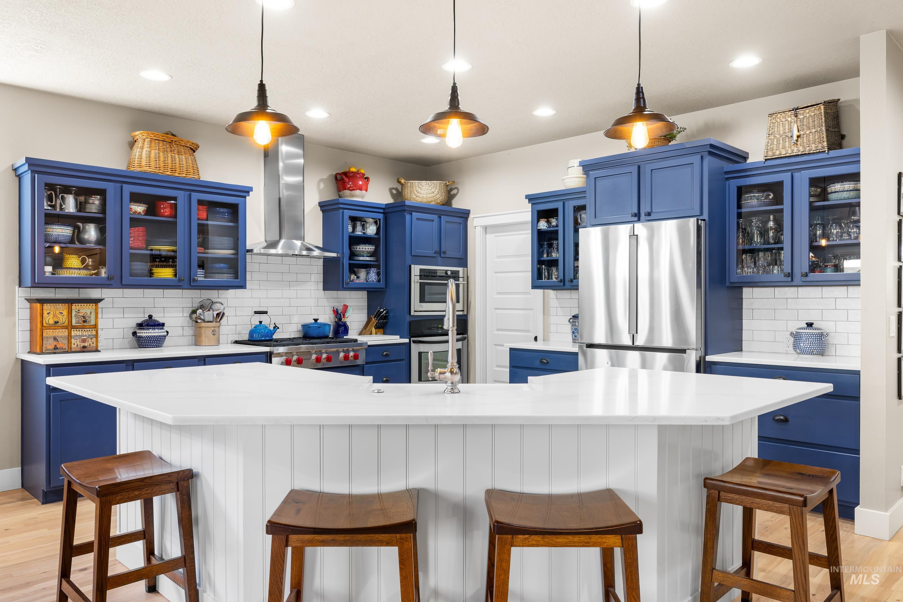 Kitchen with blue cabinets, glass insert cabinets, a kitchen bar, and recessed lighting