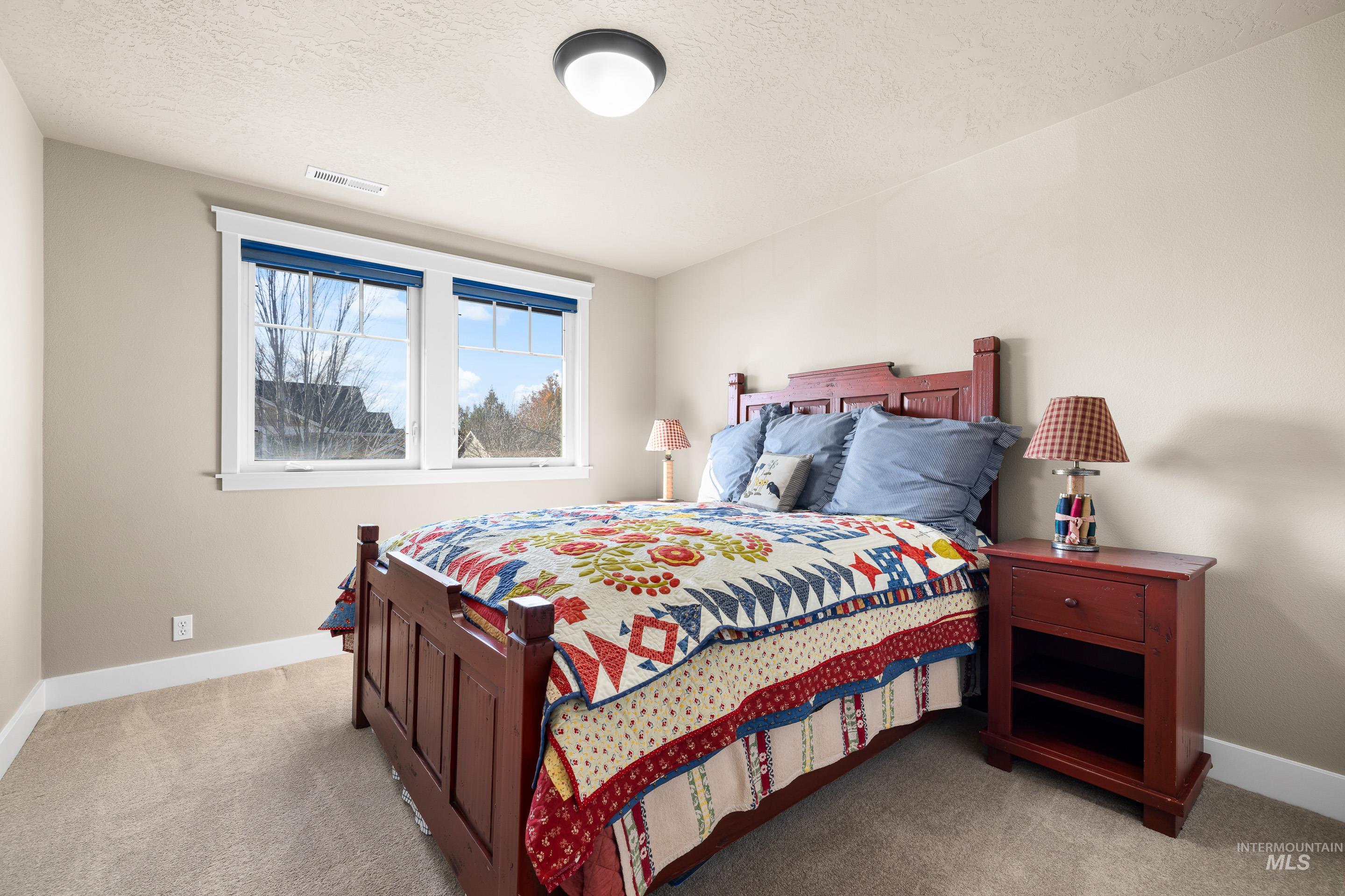 Bedroom with light colored carpet and a textured ceiling