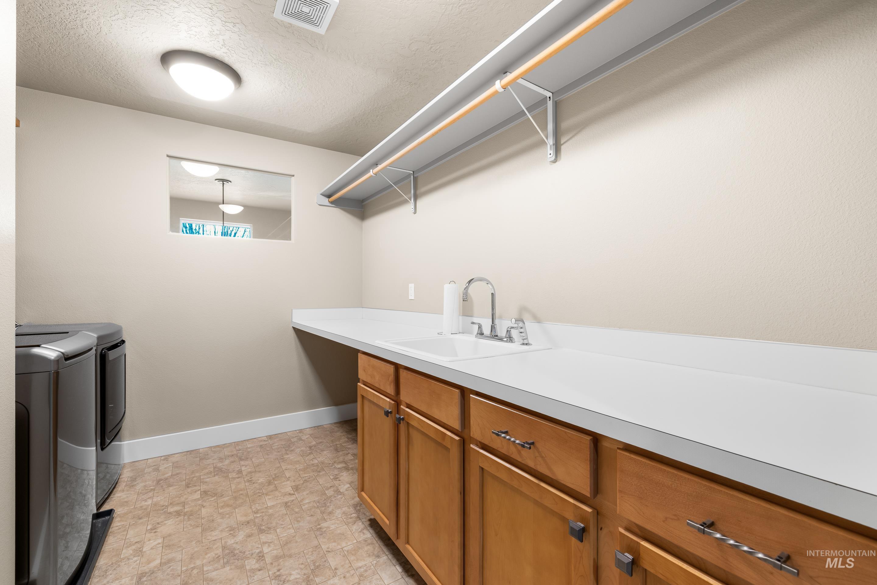 Laundry room with a textured ceiling and washing machine and clothes dryer