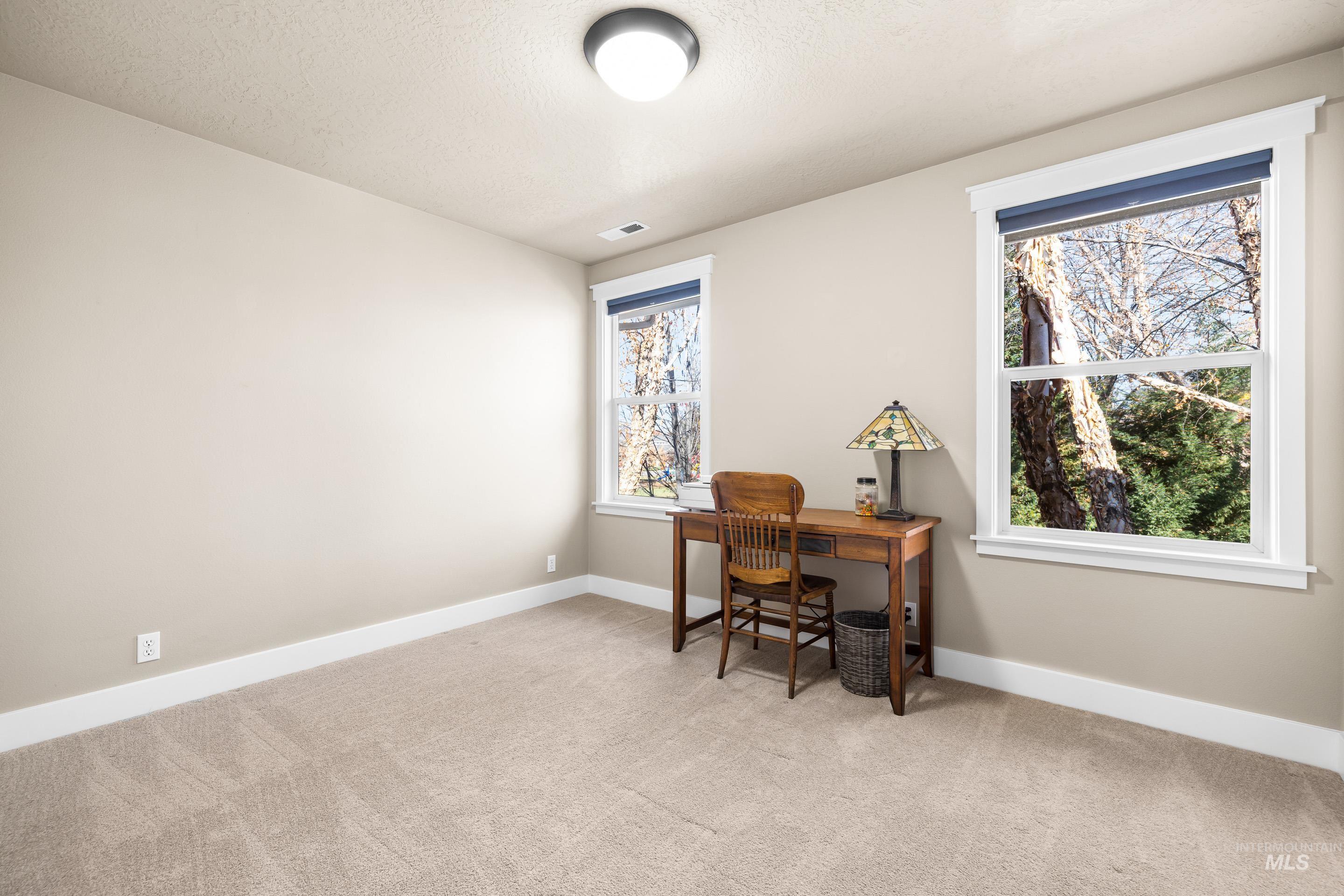 Office area featuring light carpet and a textured ceiling