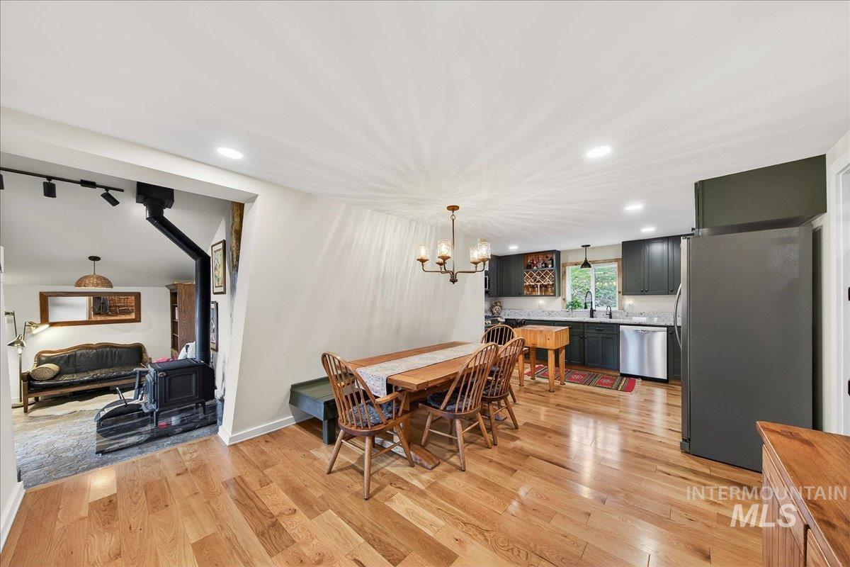 Dining space featuring a wood stove, light wood-style flooring, and a chandelier