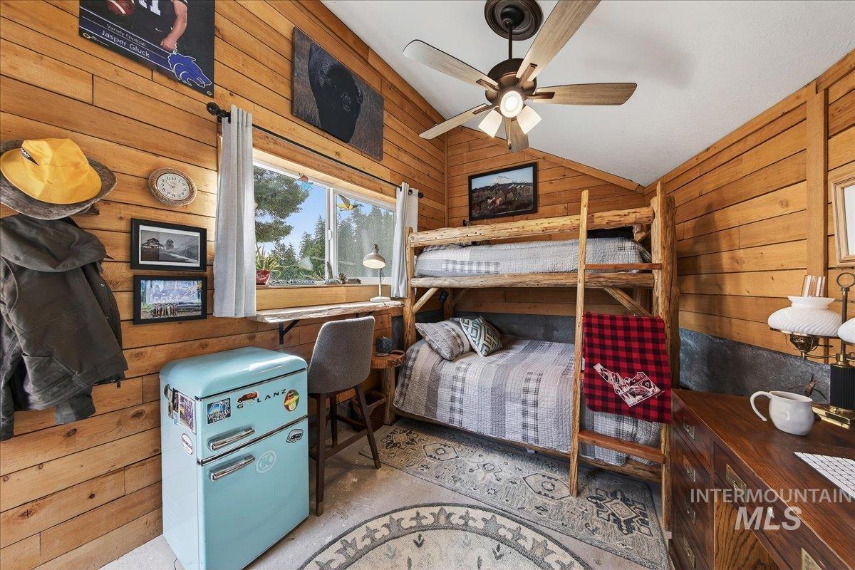 Bunkhouse featuring wood walls, ceiling fan, and lofted ceiling