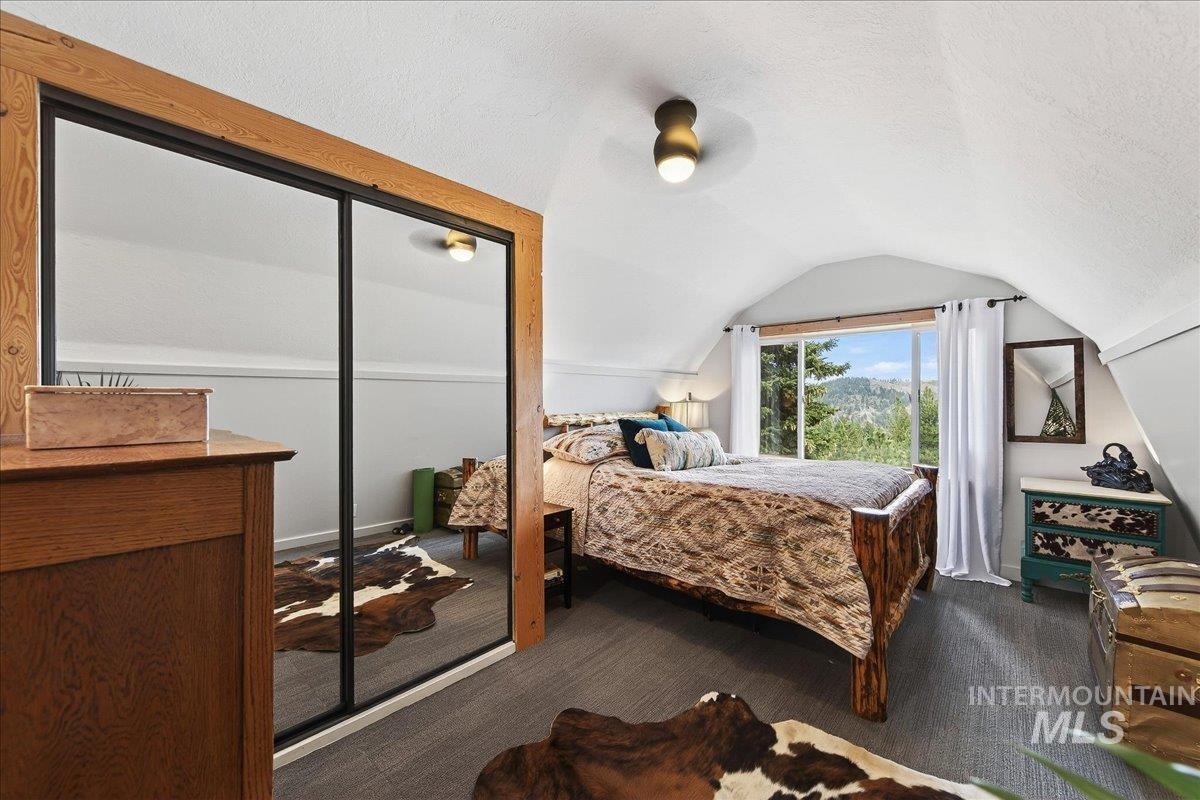 Bedroom featuring a ceiling fan, a closet, dark carpet, and a textured ceiling