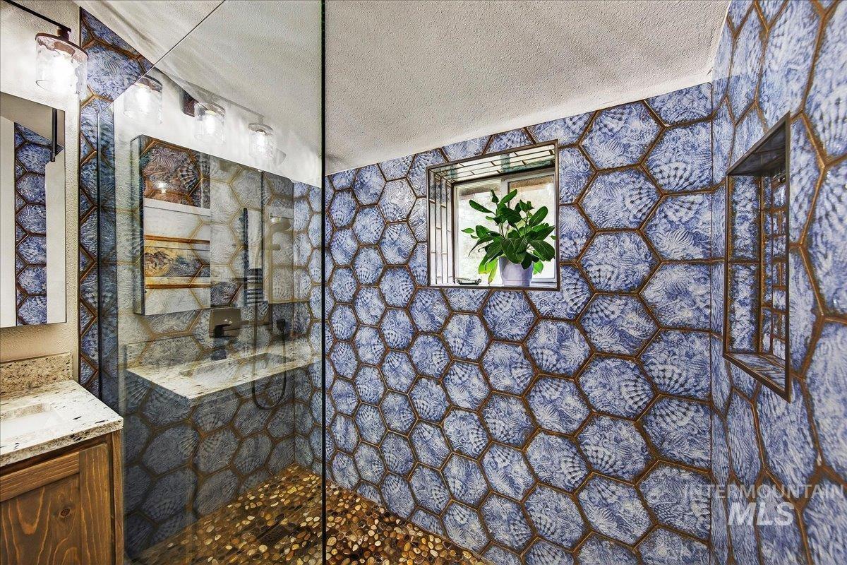 Bathroom featuring a textured ceiling, a walk in shower, and vanity