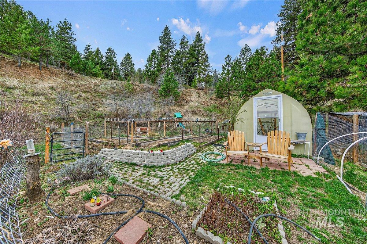 Fenced backyard with a vegetable garden, an outdoor structure, view of scattered trees, and an exterior structure