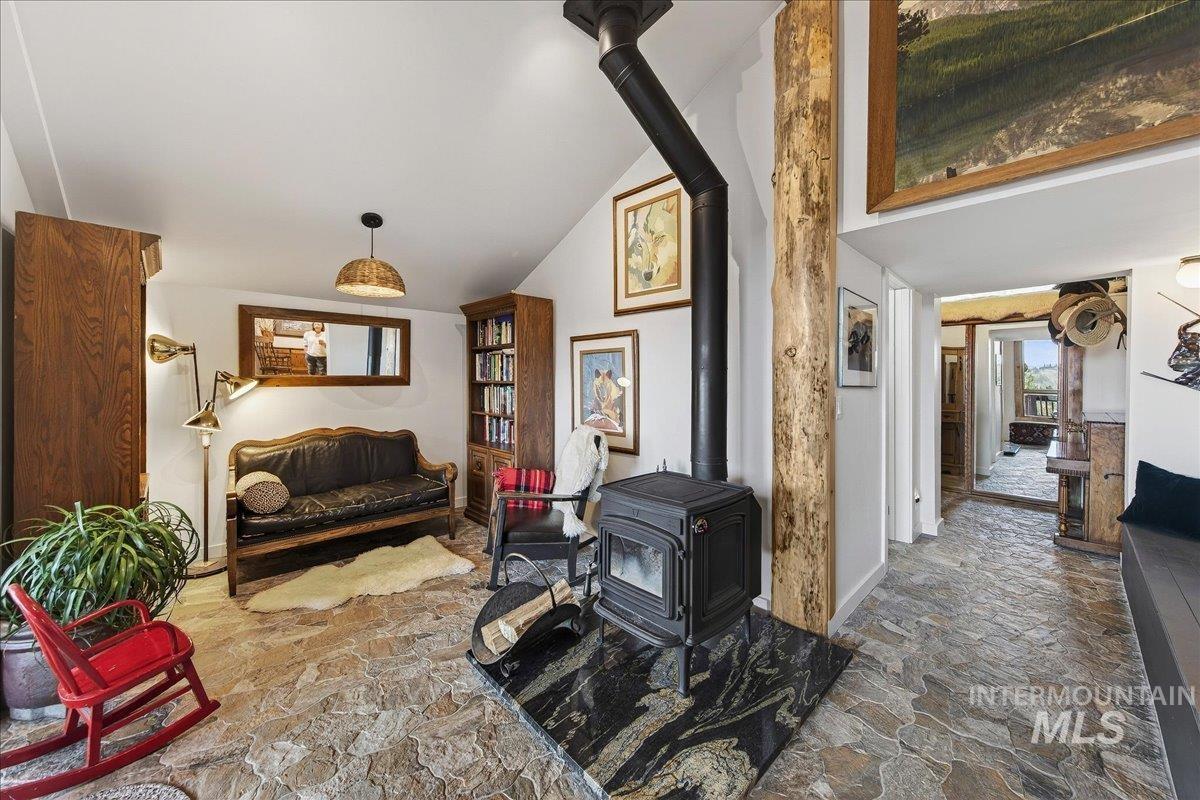 Living area with stone looking pavers, a wood stove, and vaulted ceiling
