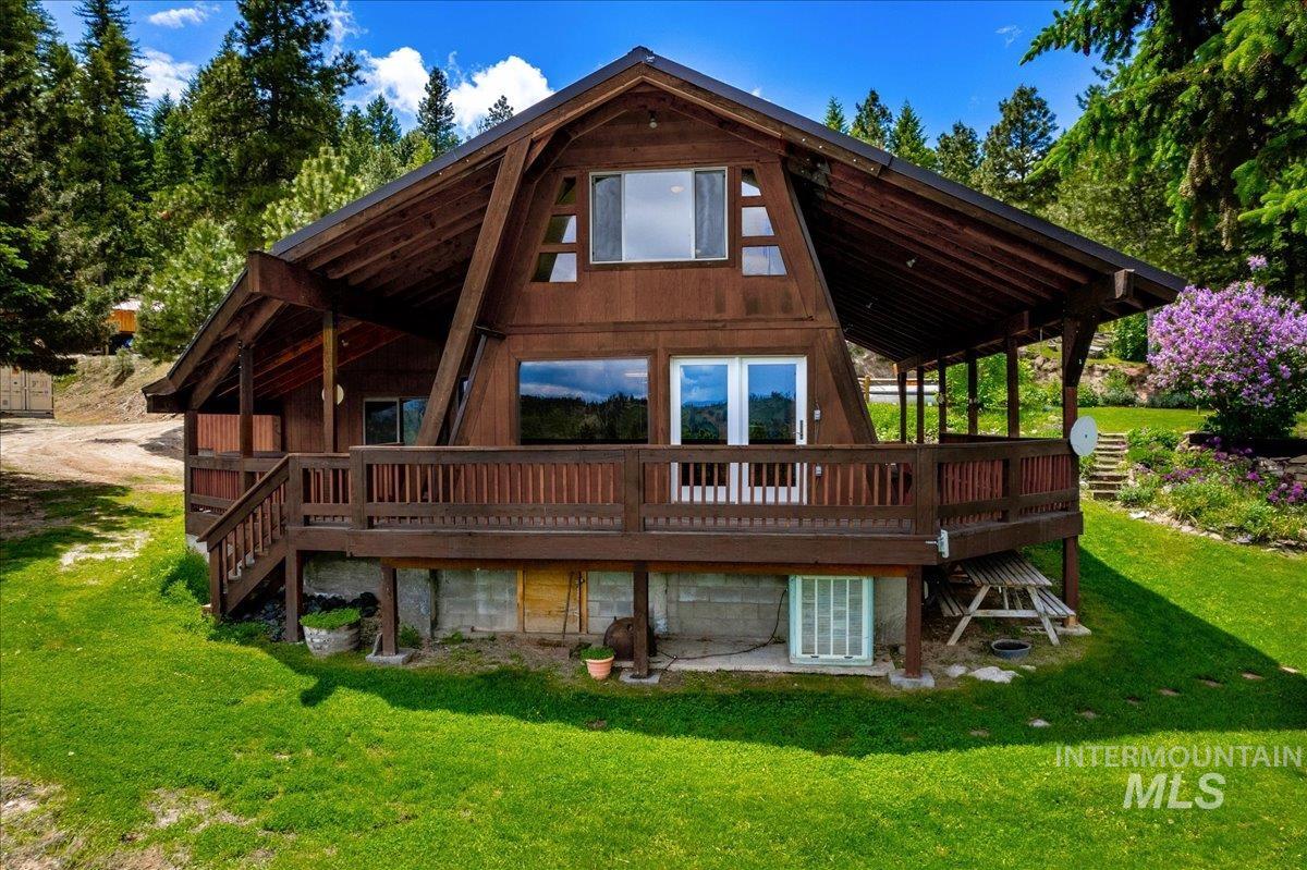 Rear view of property featuring a deck and a lawn