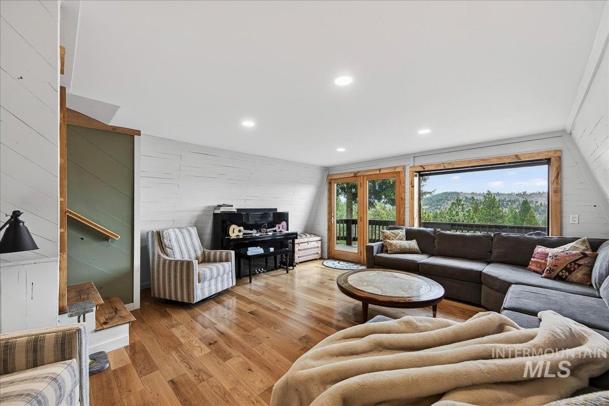 Living room featuring light wood-style floors, wood walls, and recessed lighting