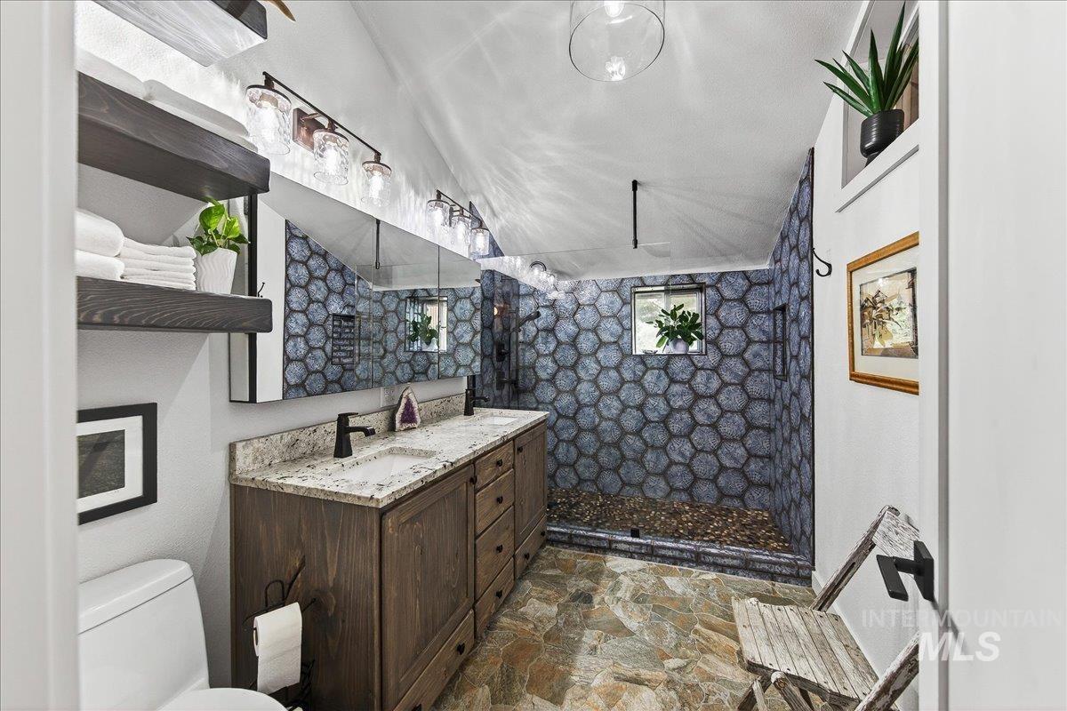 Bathroom with walk in shower, vanity, and stone flooring