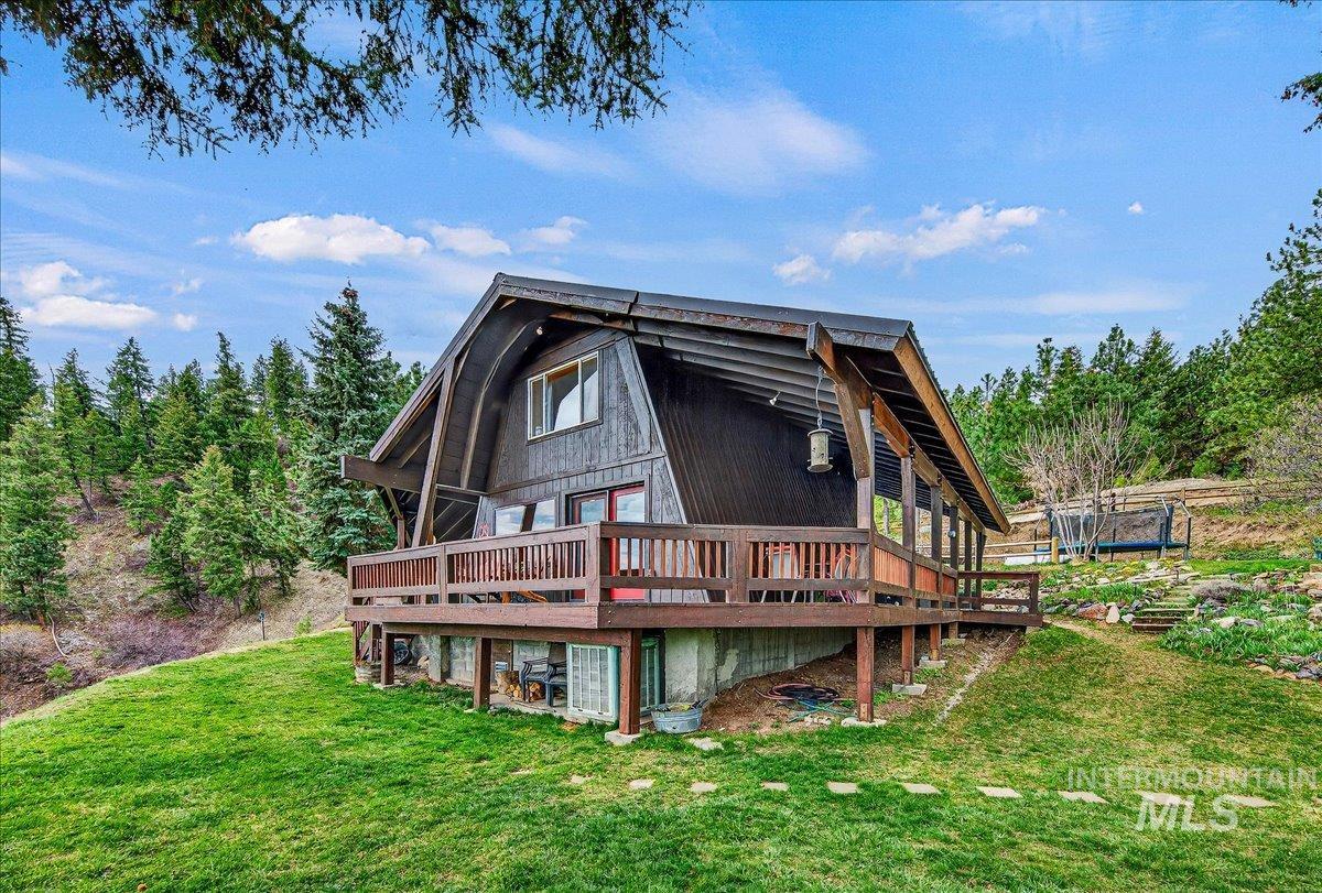 Back of property featuring a deck, a yard, and a trampoline