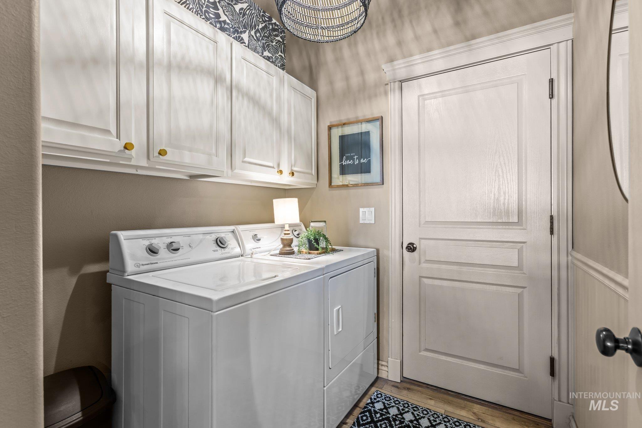 Laundry room with cabinet space, washing machine and clothes dryer, and light wood-style flooring