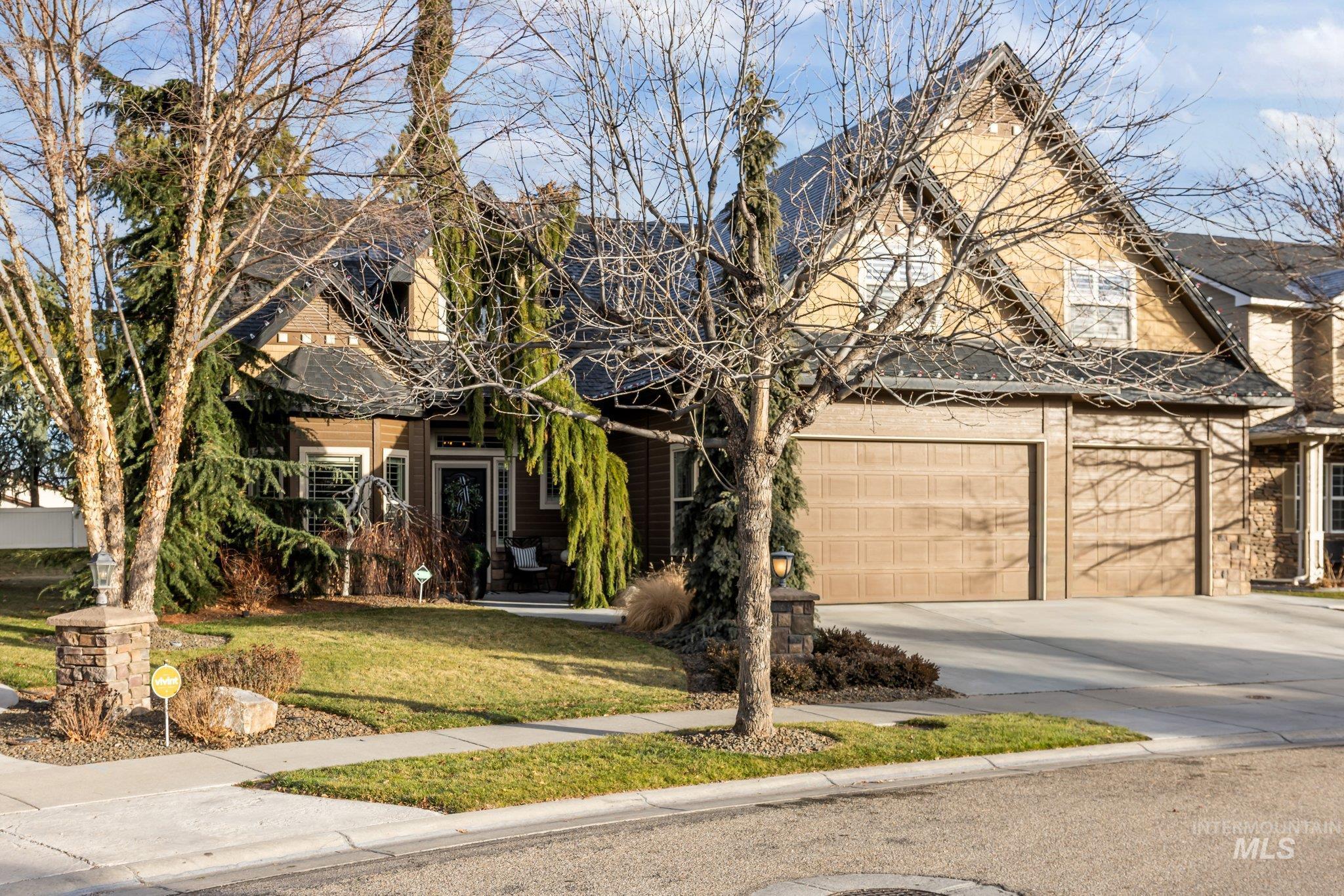 View of front facade with a front yard, driveway, a garage, and stone siding