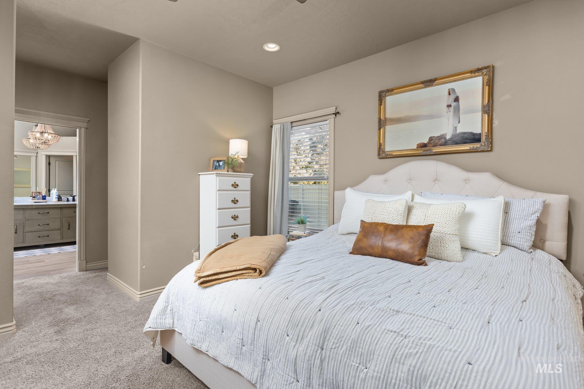 Carpeted bedroom with connected bathroom, a chandelier, and recessed lighting