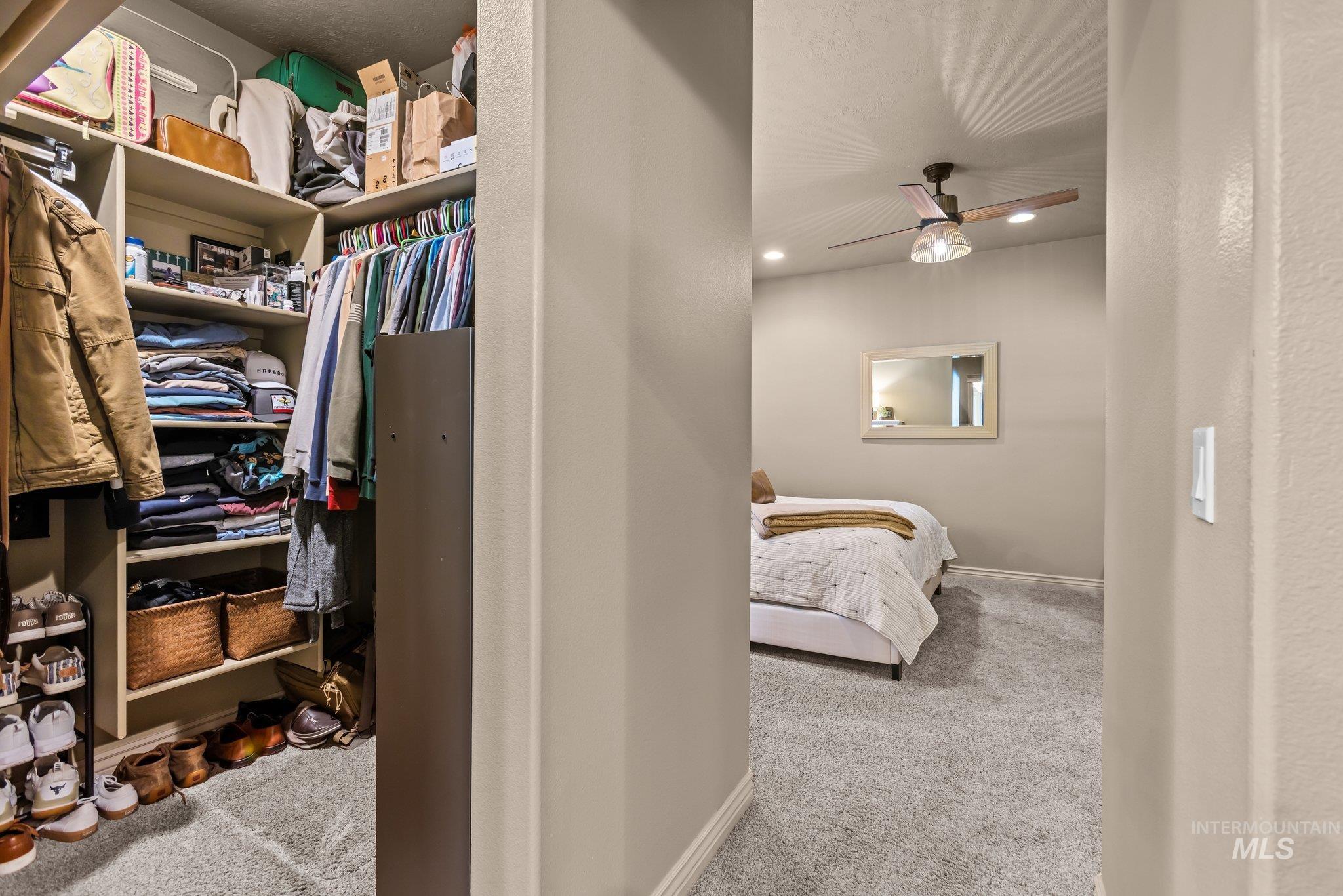 Spacious closet featuring light colored carpet and a ceiling fan