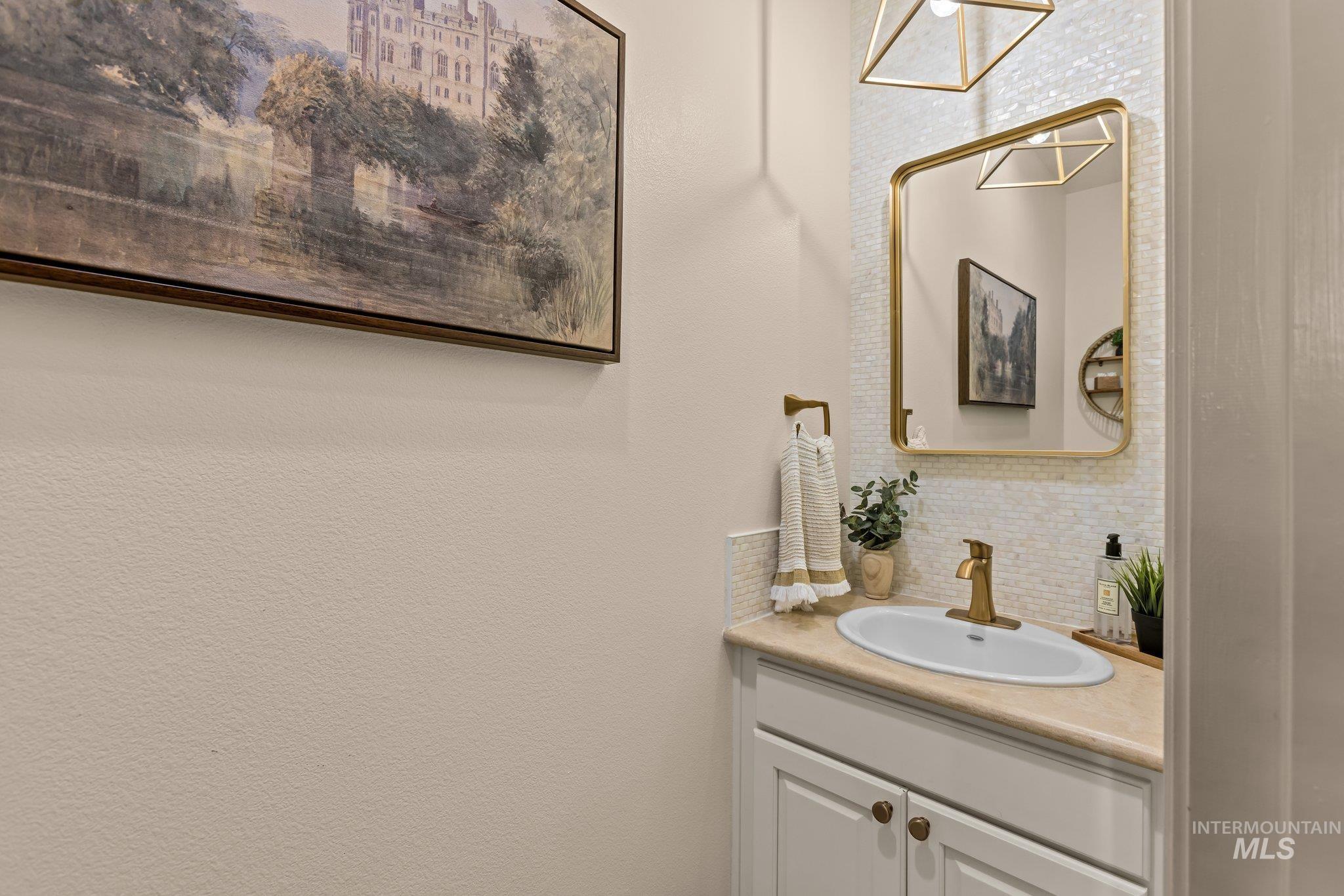 Bathroom featuring decorative backsplash, vanity, and a textured wall
