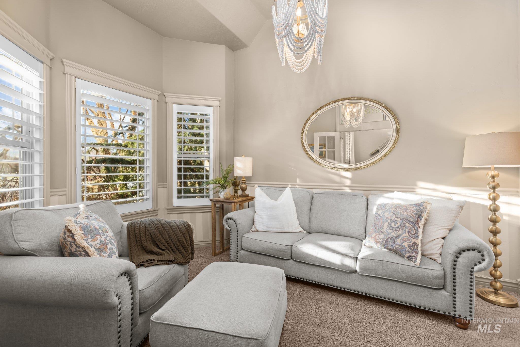 Living area featuring carpet flooring, healthy amount of natural light, and a chandelier