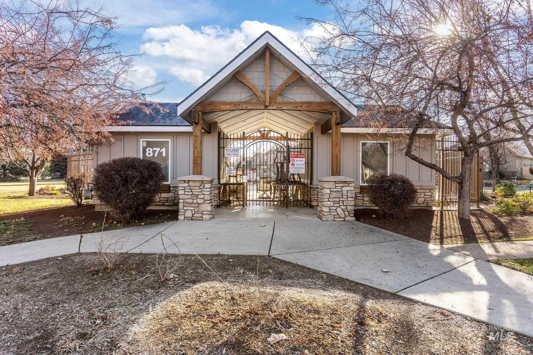 View of front of house featuring stone siding, a gate, and roof with shingles