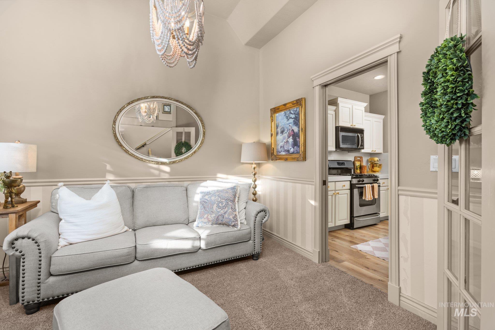 Living room with light carpet, wainscoting, and a chandelier