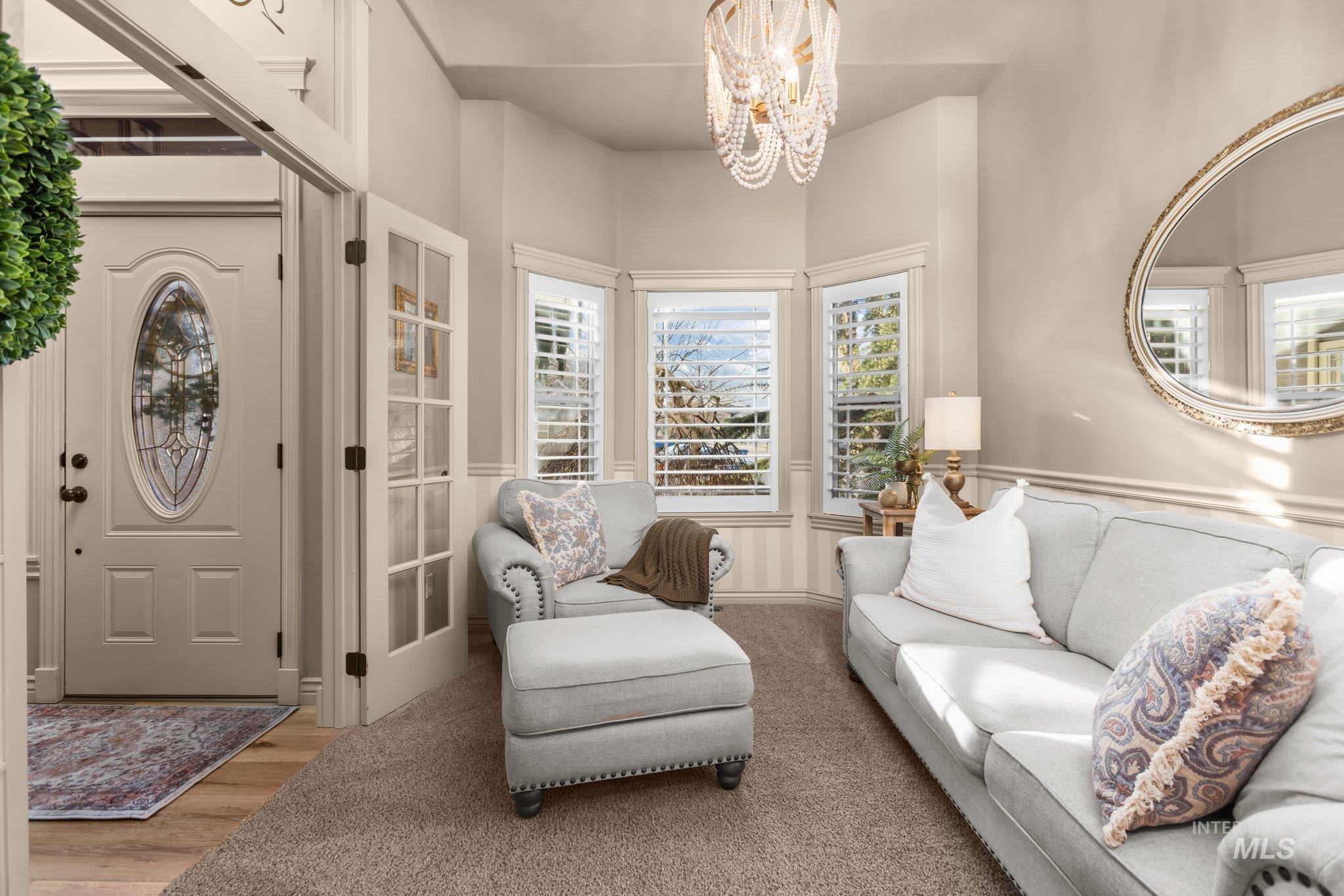 Foyer entrance featuring a chandelier, wood finished floors, and a wainscoted wall