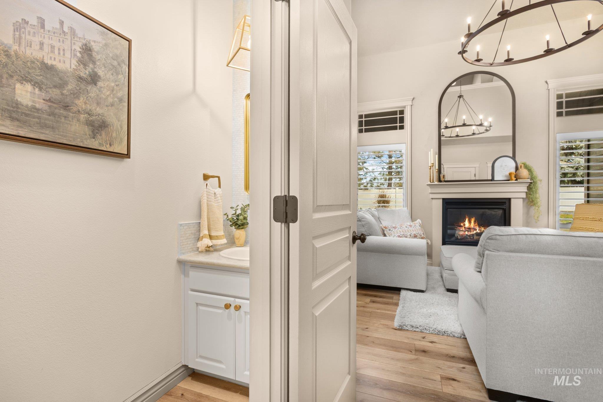 Living area featuring a glass covered fireplace, light wood-style flooring, and a chandelier