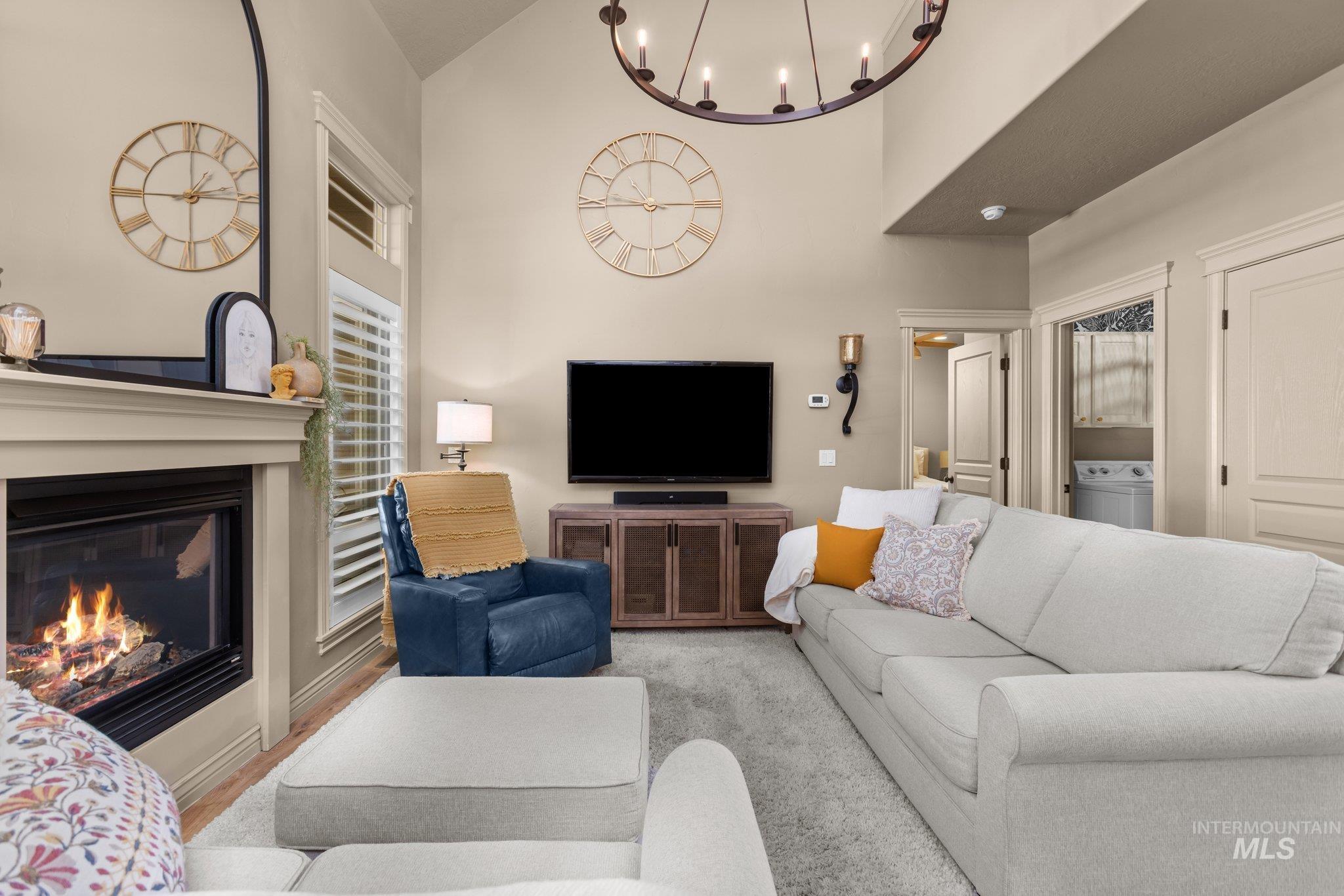 Living area with a glass covered fireplace, washer / dryer, a towering ceiling, and a chandelier