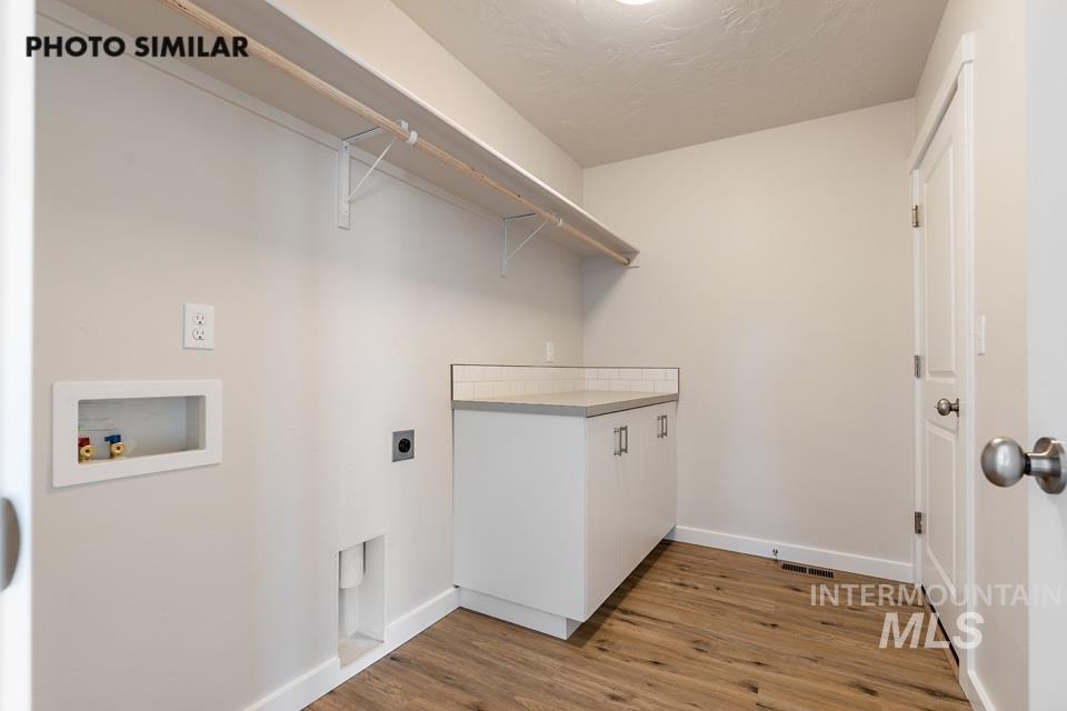 Laundry room featuring light wood-style flooring, hookup for an electric dryer, hookup for a washing machine, and cabinet space
