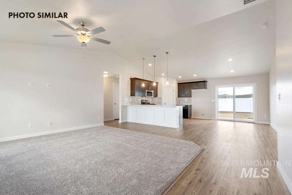 Unfurnished living room with vaulted ceiling, a ceiling fan, light wood finished floors, and recessed lighting