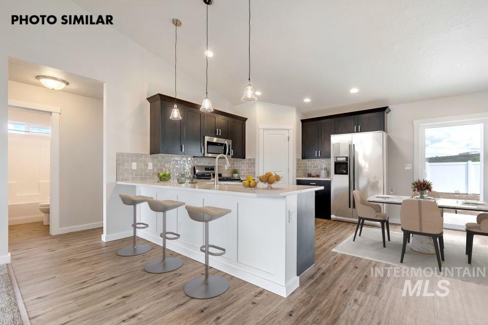 Kitchen with plenty of natural light, a breakfast bar area, stainless steel appliances, hanging light fixtures, and recessed lighting
