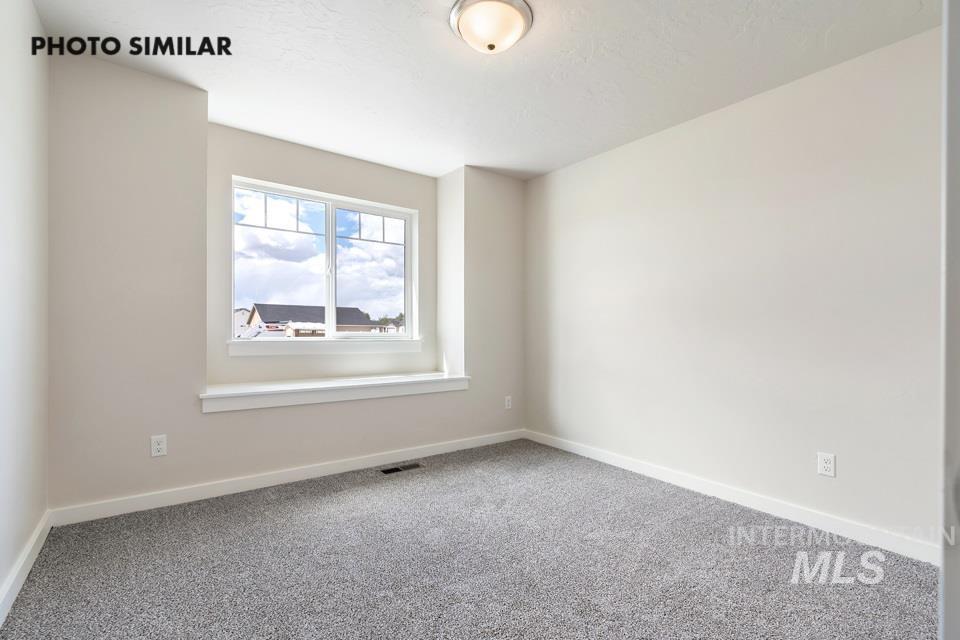 Carpeted spare room featuring baseboards