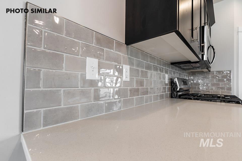 Kitchen view of tasteful backsplash, gas range oven, and light stone countertops
